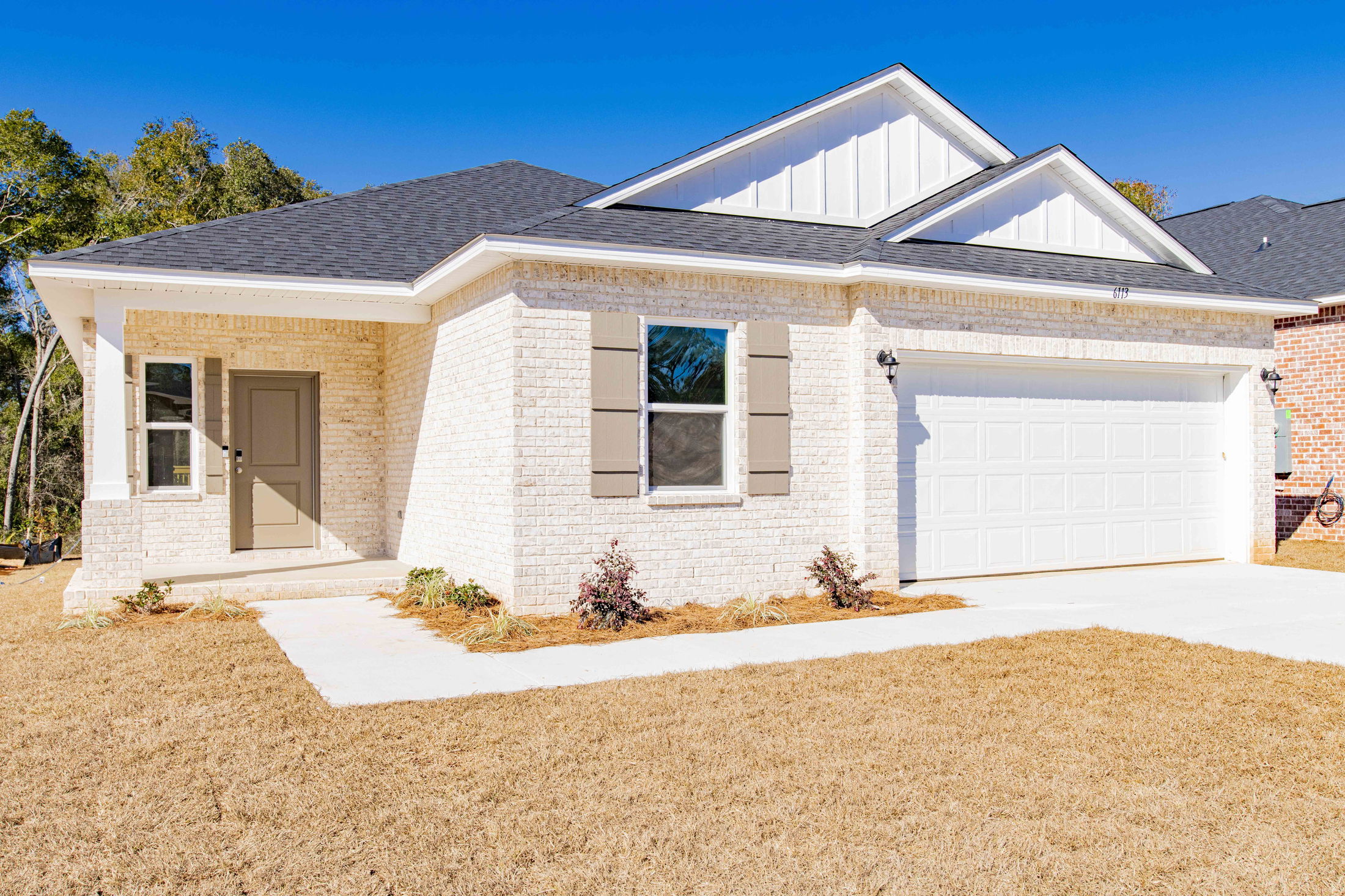Newly-built, single-story brick house with a two-car garage and neatly landscaped front yard.