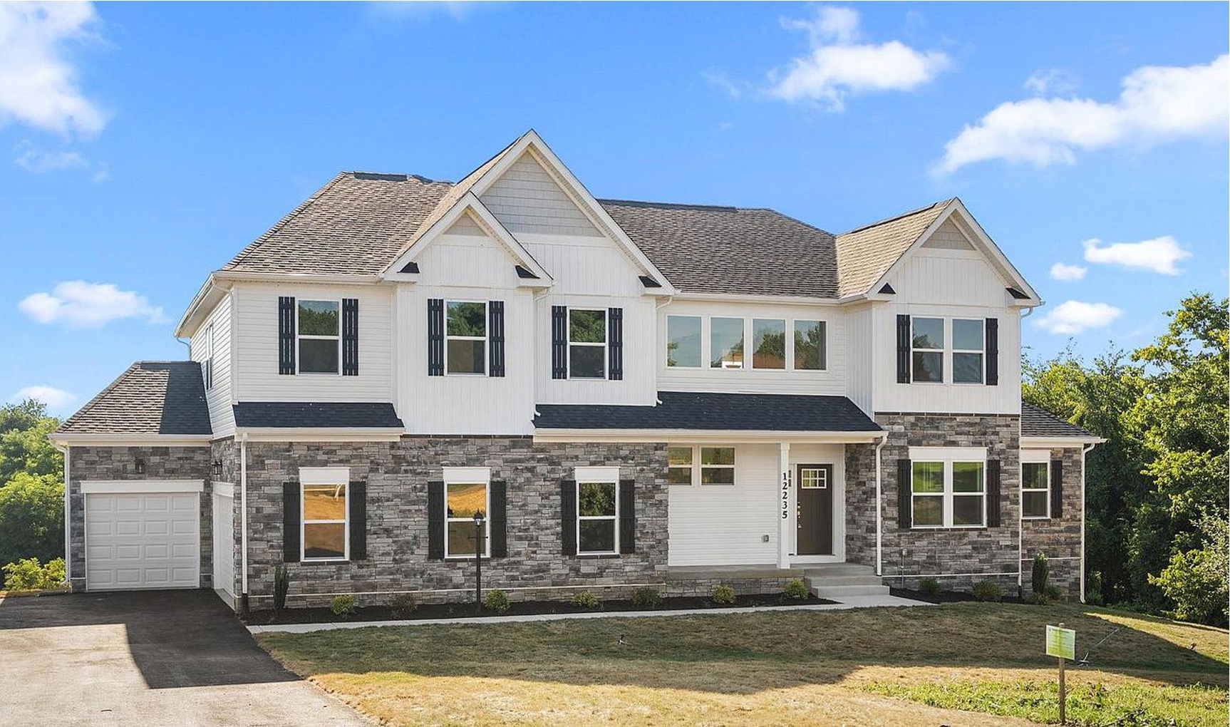 Modern two-story suburban house with brick and white siding exterior, under a blue sky.