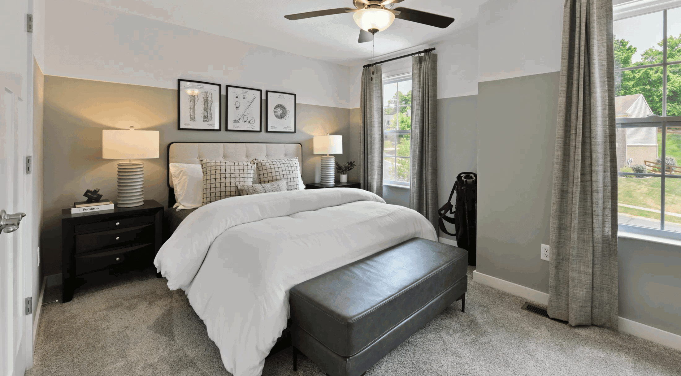 Modern bedroom interior with a cozy bed, decorative pillows, bedside tables with lamps, stylish wall art, and large windows with curtains.