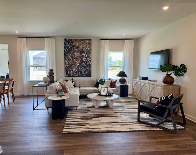Modern living room with stylish decor, featuring a beige sectional sofa, abstract wall art, and a flat-screen TV on a light-toned wooden console.