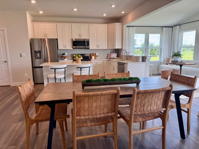 Modern kitchen and dining area with wooden furniture, stainless steel appliances, and large windows offering a scenic view.