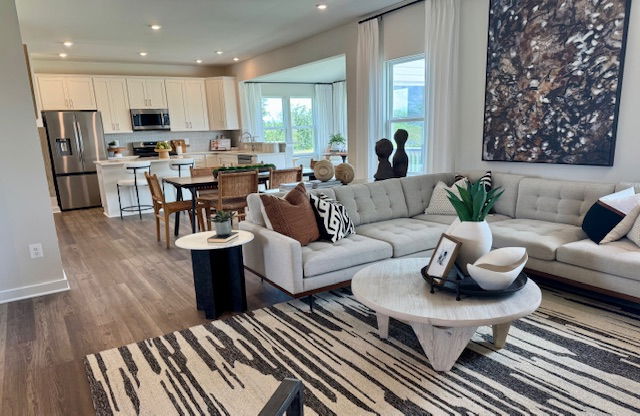 Modern open-concept living room and kitchen with stylish neutral decor, featuring a sectional sofa, abstract art, and a contemporary dining area.