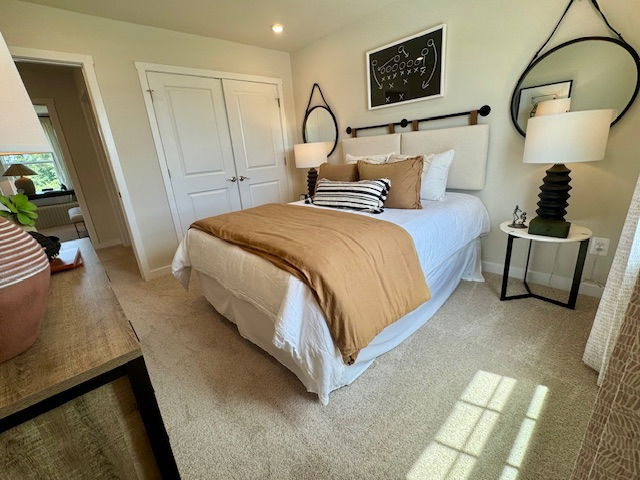 Modern bedroom with stylish decor featuring a neatly made bed with beige and white bedding, flanked by round mirrors and black lamps on side tables.