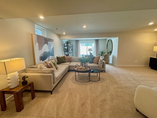 Spacious modern living room with beige carpet, L-shaped sofa, abstract wall art, and large windows for natural light.