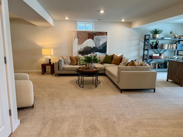 Modern basement living room featuring a neutral-toned sectional sofa, abstract art, and stylish shelving.