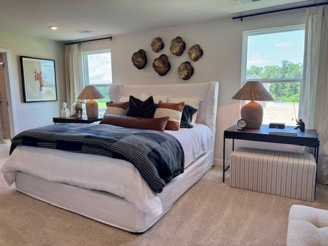 Modern bedroom with elegant decor, featuring a large bed, textured pillows, side tables with lamps, and artistic wall accents.