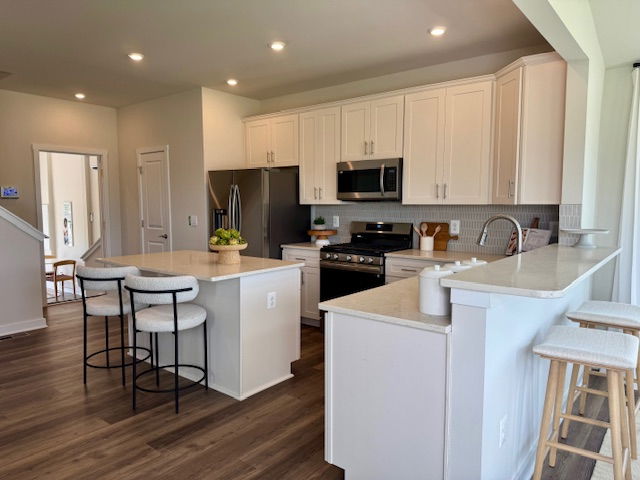Modern kitchen with white cabinets, stainless steel appliances, and a center island with barstools.