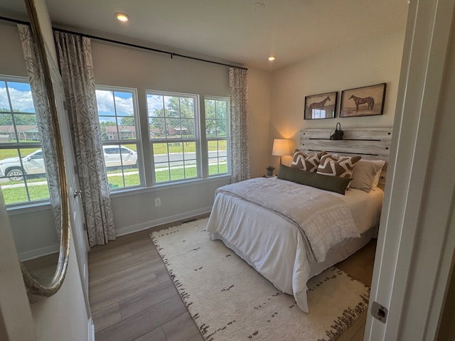 Cozy bedroom with large windows, stylish decor, and a neatly made bed with decorative pillows.