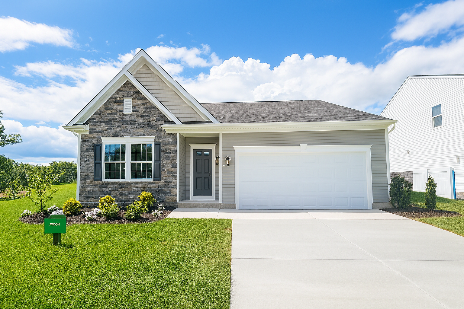 Freshly constructed suburban house with stone façade, spacious driveway, and well-maintained lawn under a bright blue sky.