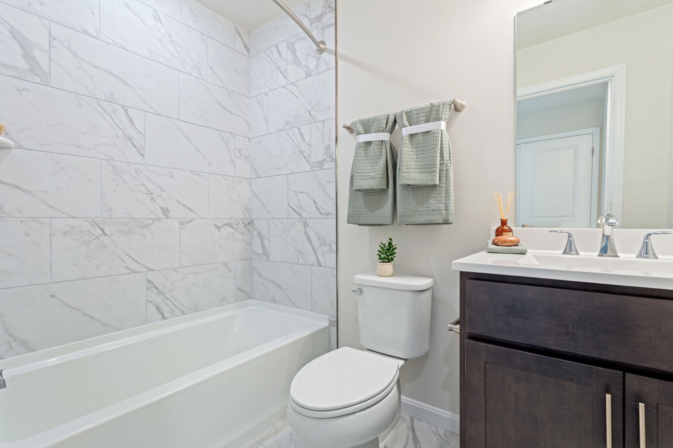 Modern bathroom with a marble-tiled shower, white bathtub, and elegant fixtures.