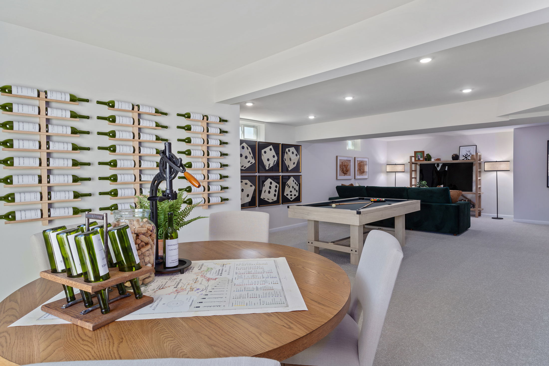 Stylish basement recreation room featuring a wine bottle wall display, billiards table, and contemporary decor.