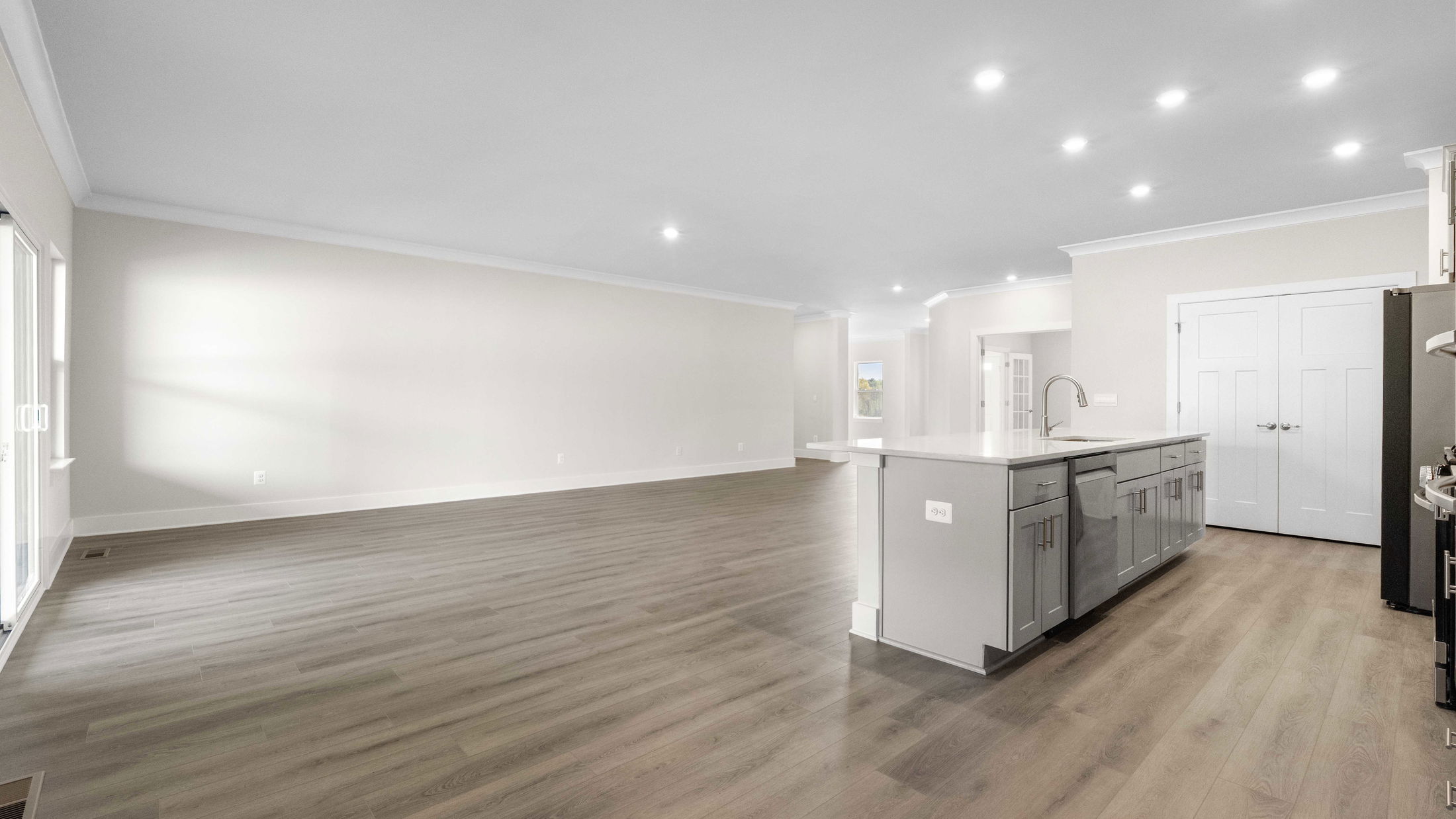 Modern open-concept kitchen and living area with light wood flooring, recessed lighting, and an island.