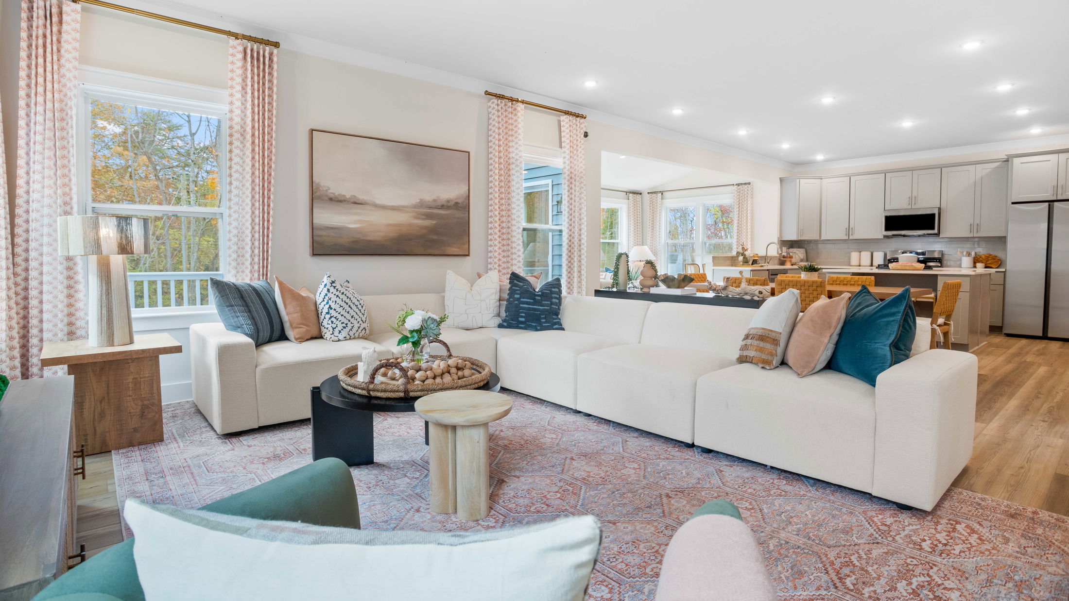 Bright and modern open-concept living room with a cozy sectional sofa, chic decor, and adjacent kitchen area.
