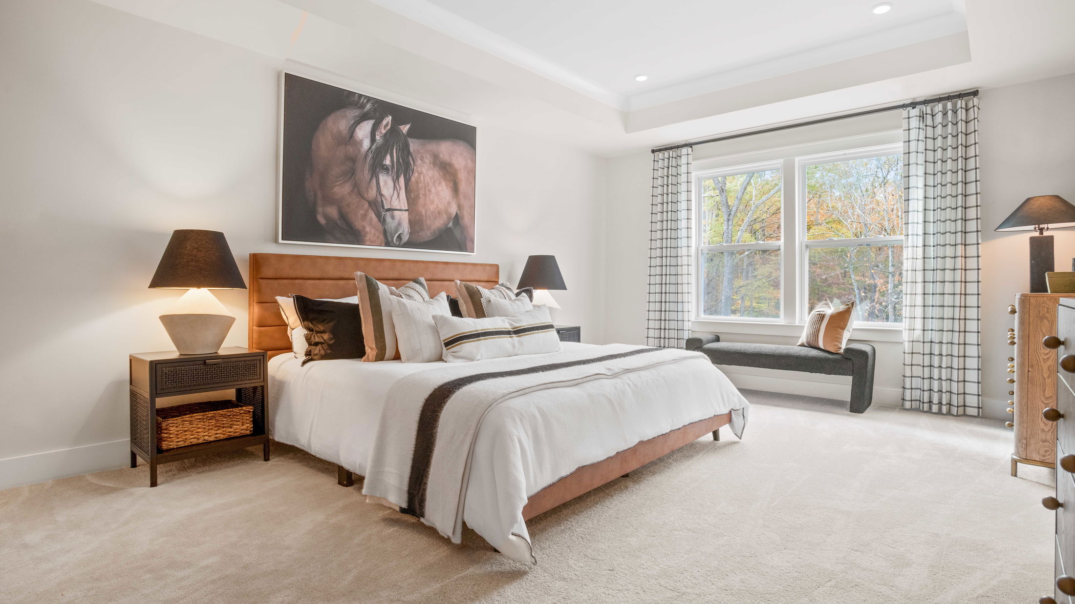 Modern bedroom with a plush bed, large window, and stylish decor featuring a horse painting above the headboard.