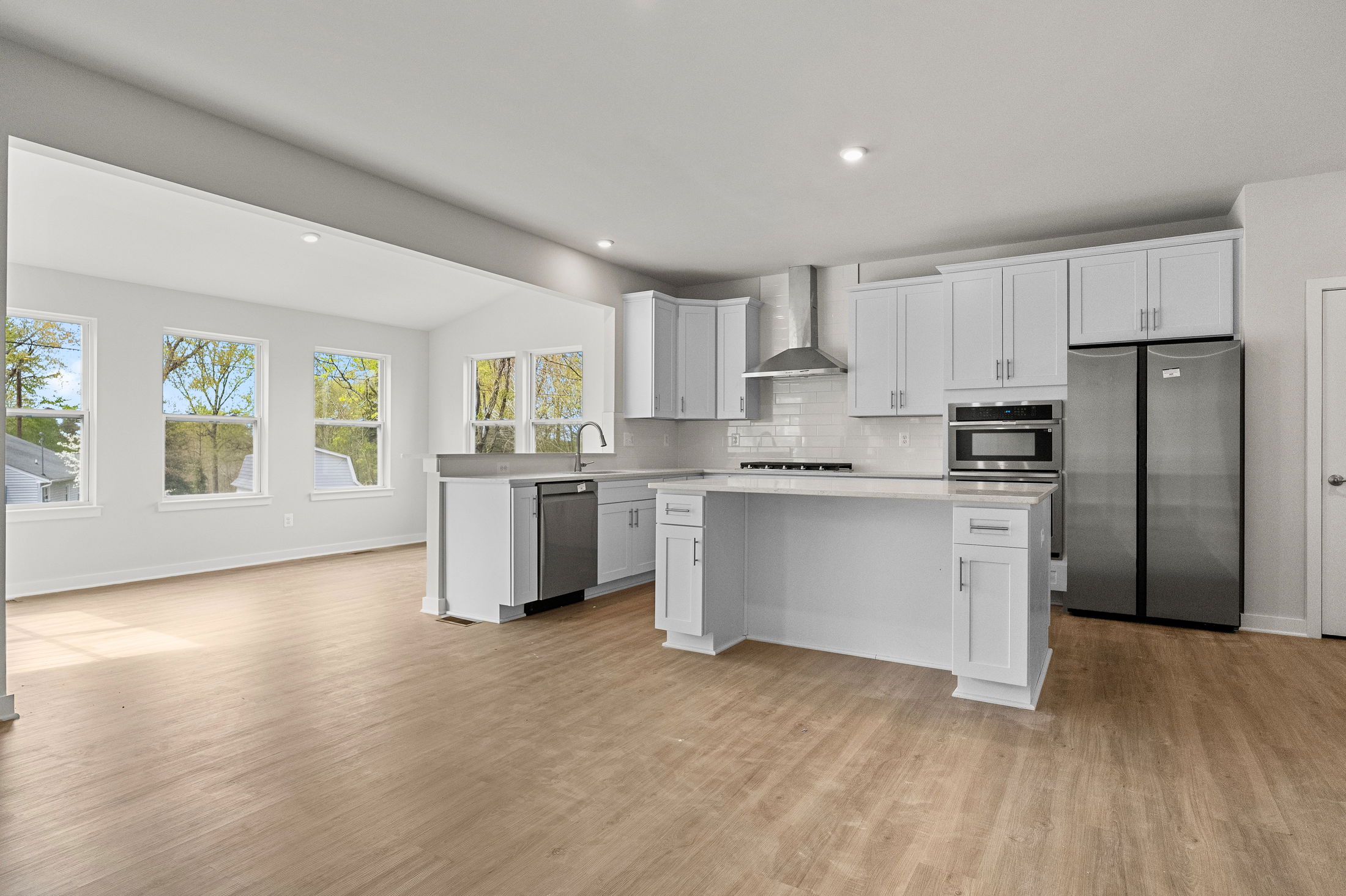 Modern kitchen interior with white cabinetry, stainless steel appliances, and hardwood flooring.