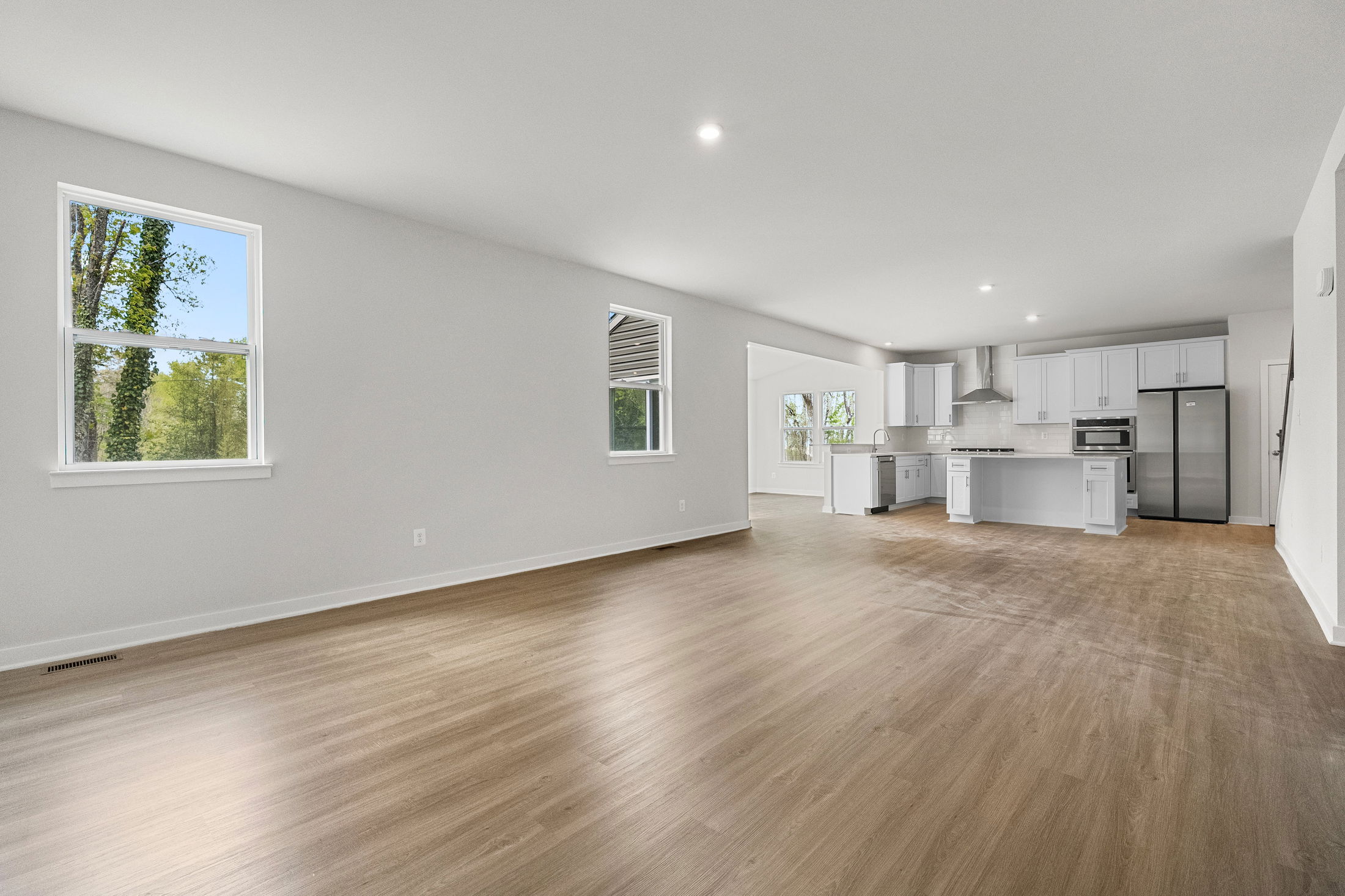 Spacious modern open-concept kitchen and living area with wood flooring and large windows.