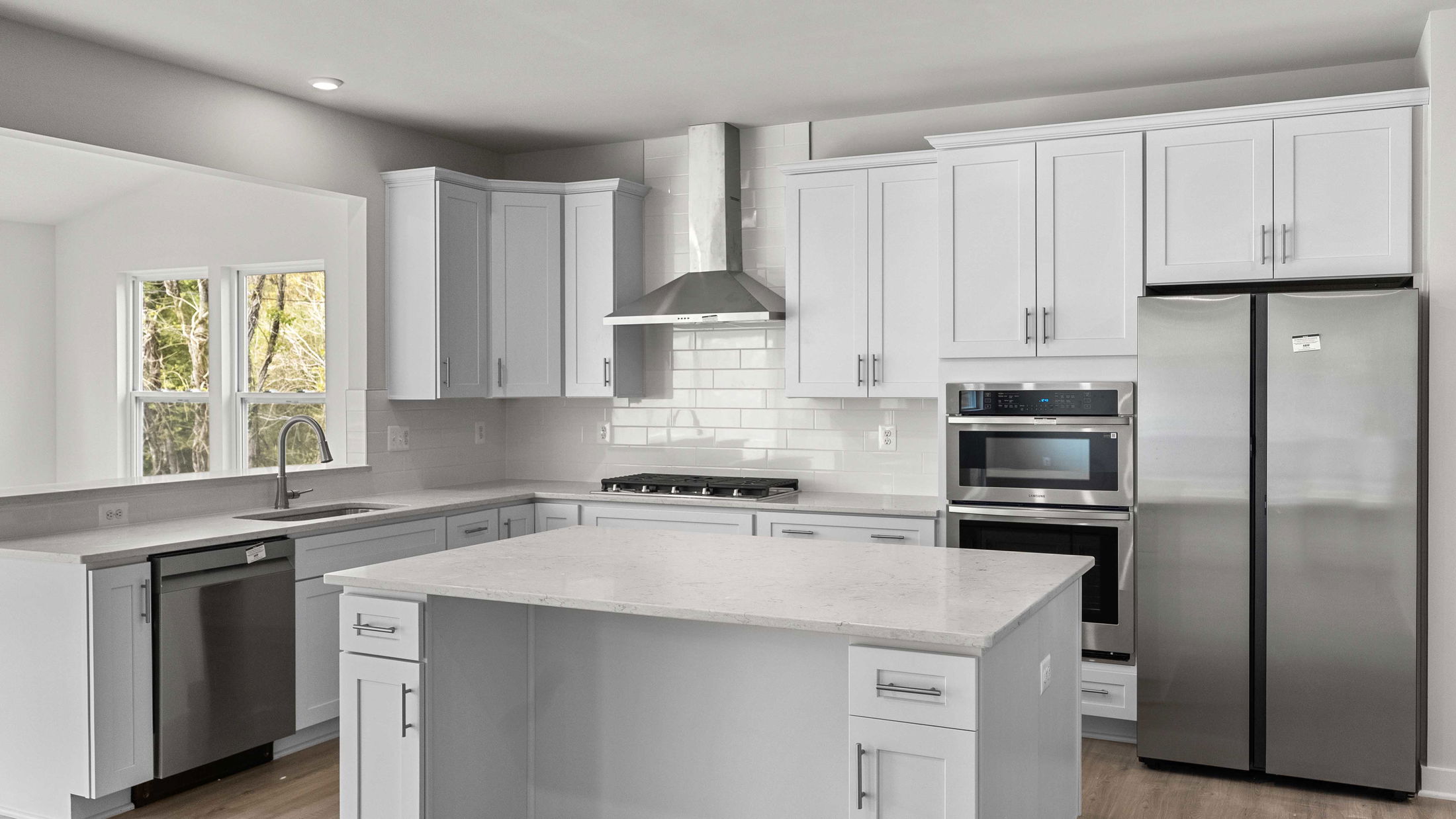 Modern kitchen with white cabinets, stainless steel appliances, and a central island.