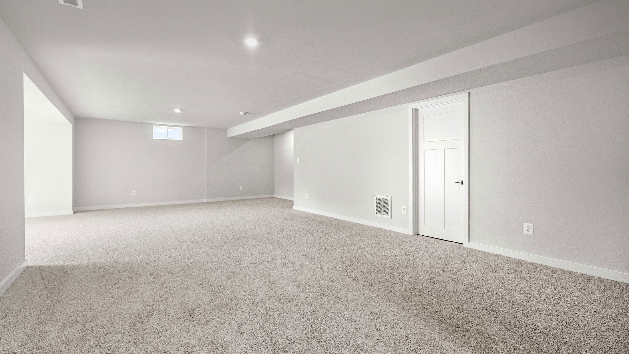 Spacious finished basement with neutral-toned walls, carpet flooring, recessed lighting, and a small window.