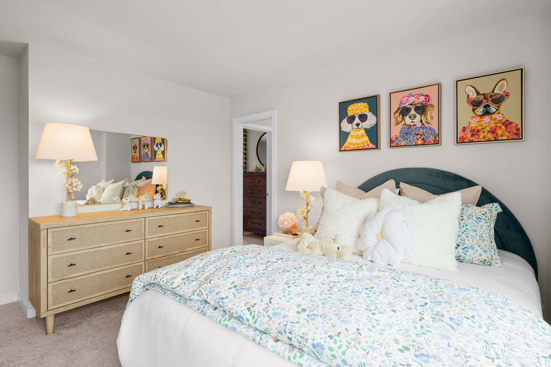 A cozy bedroom featuring a bed with floral bedding, a wooden dresser, and colorful animal-themed wall art.
