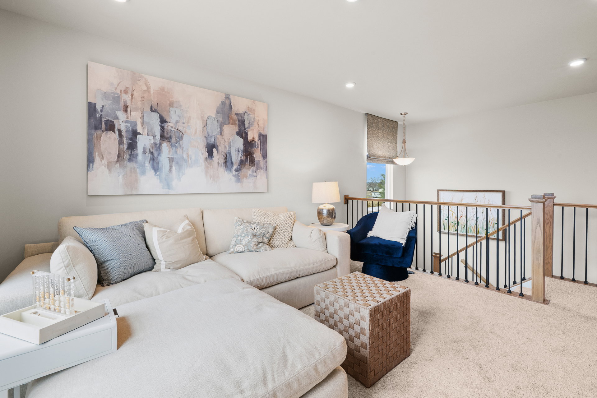 A bright living room with a large sectional sofa, decorative pillows, and a painted abstract artwork on the wall.