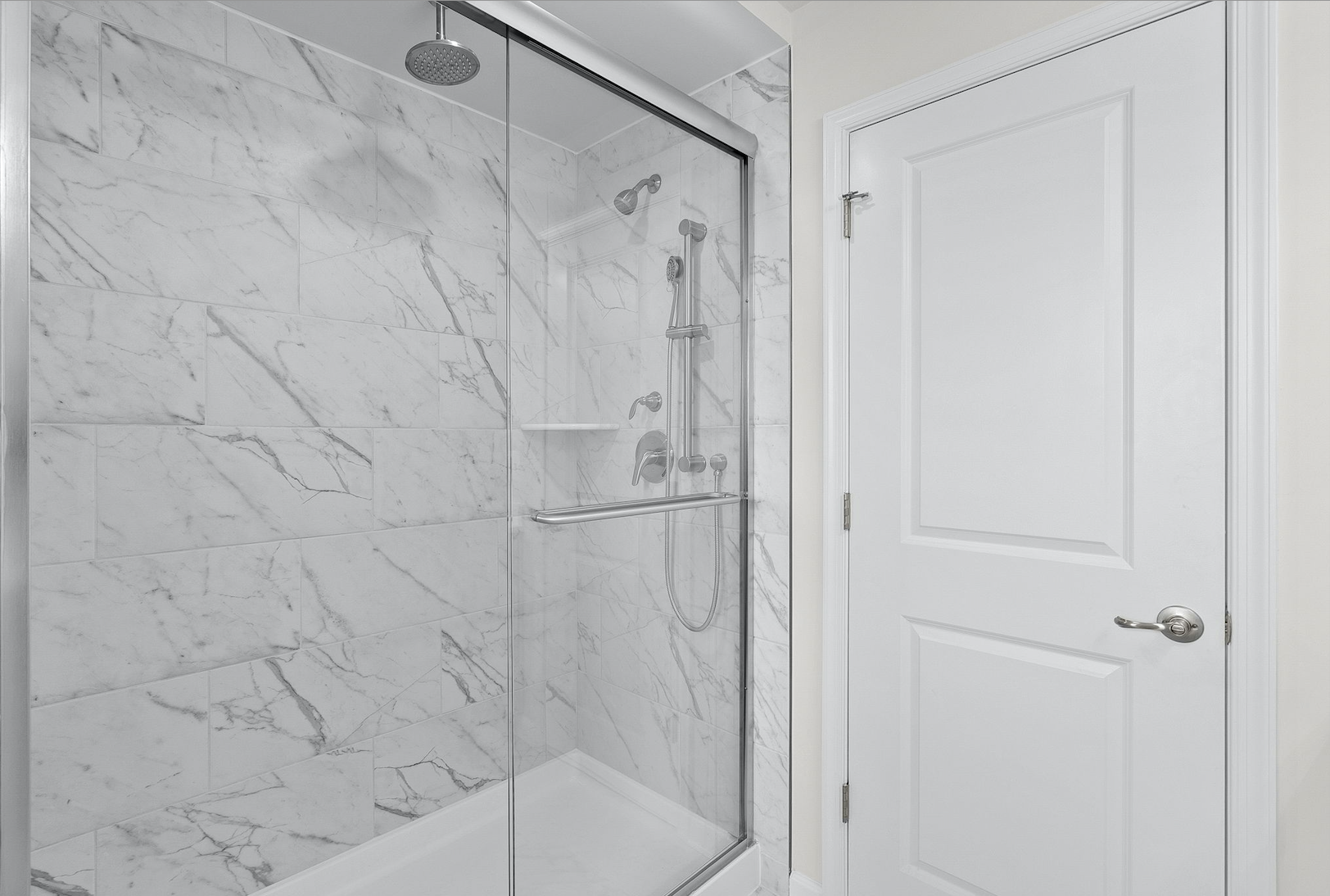 Modern bathroom with a sleek glass-enclosed shower and elegant marble tile.