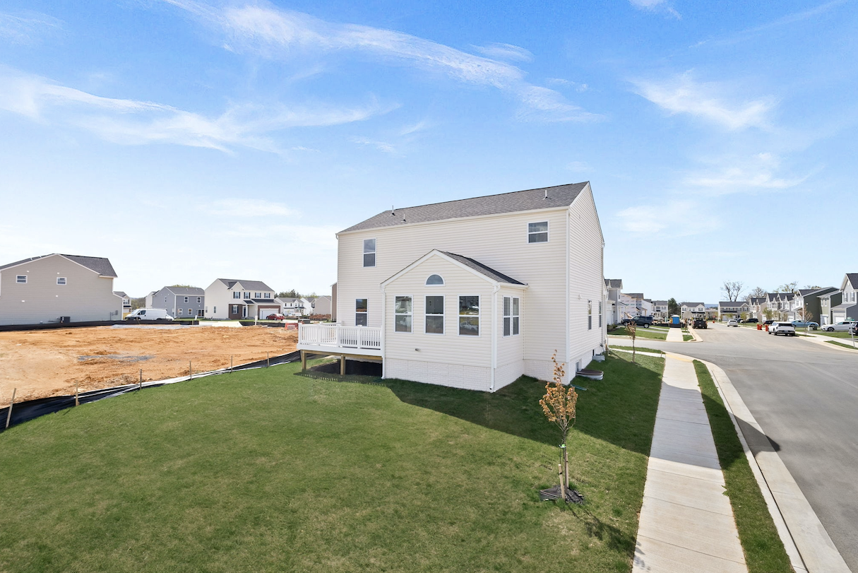 Newly constructed suburban home with a white exterior and a small backyard in a developing neighborhood.