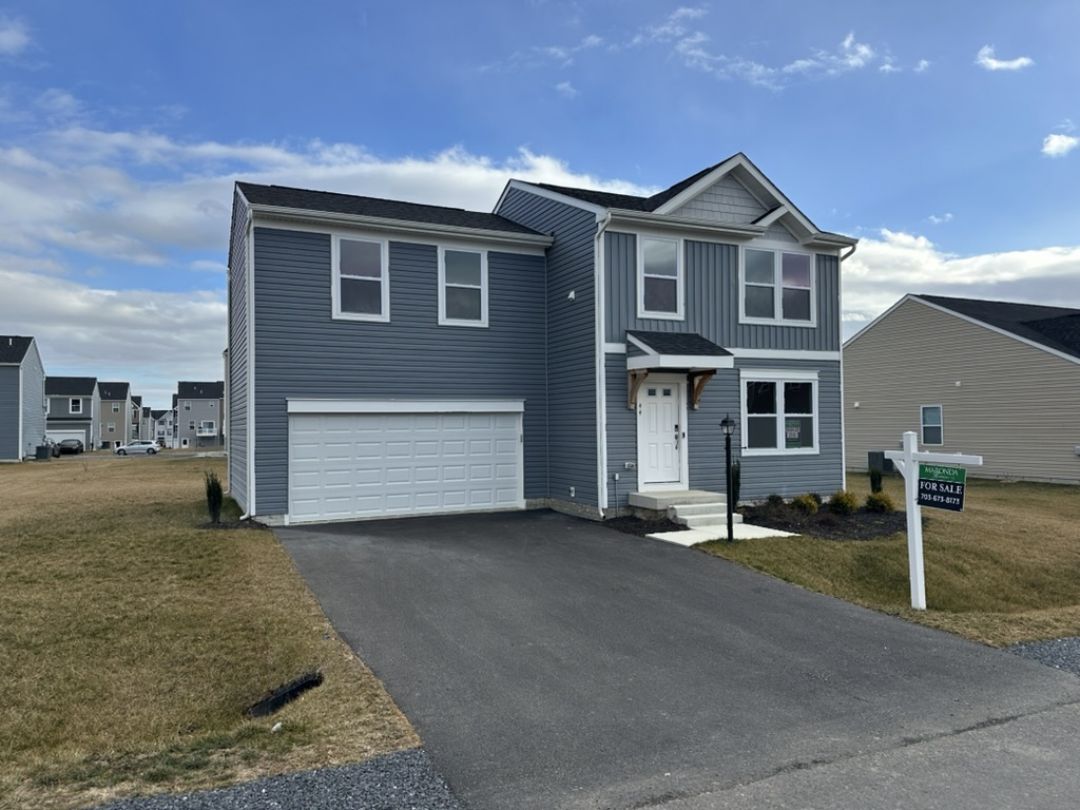 Contemporary gray two-story house for sale with a driveway and landscaped yard.