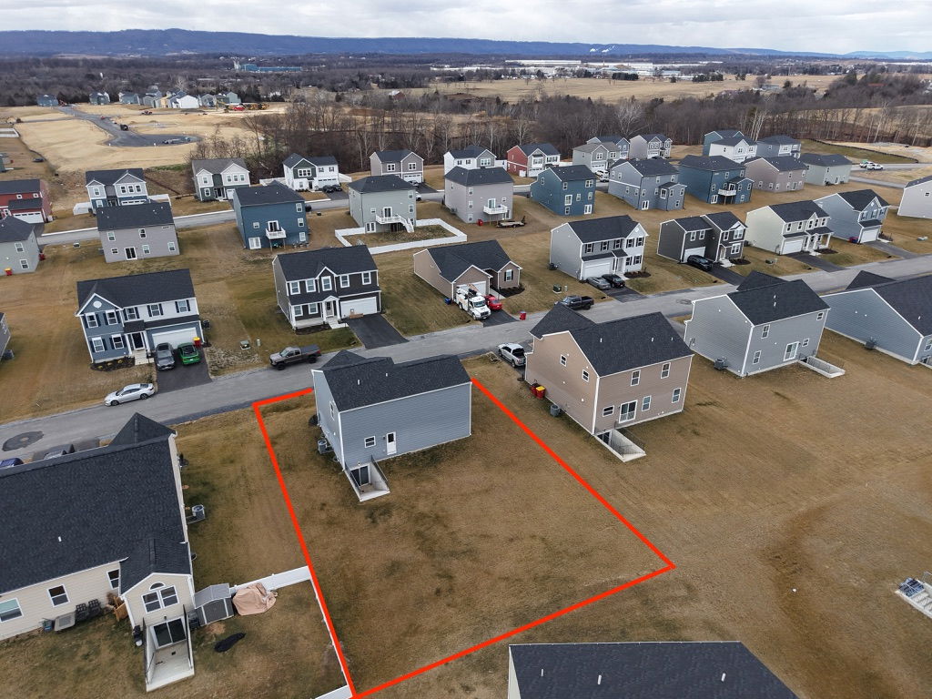 Aerial view of a residential neighborhood showcasing homes and a highlighted vacant lot for sale.