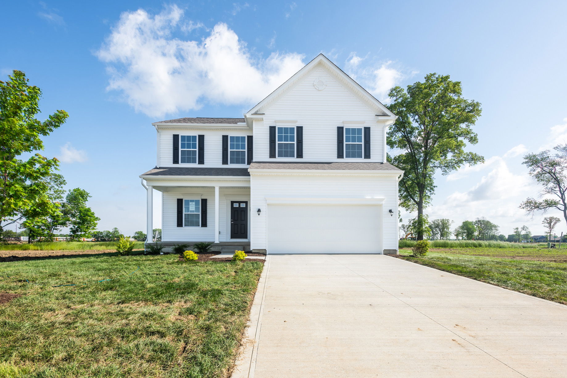 A modern two-story white house with a garage and well-maintained lawn on a clear, sunny day.