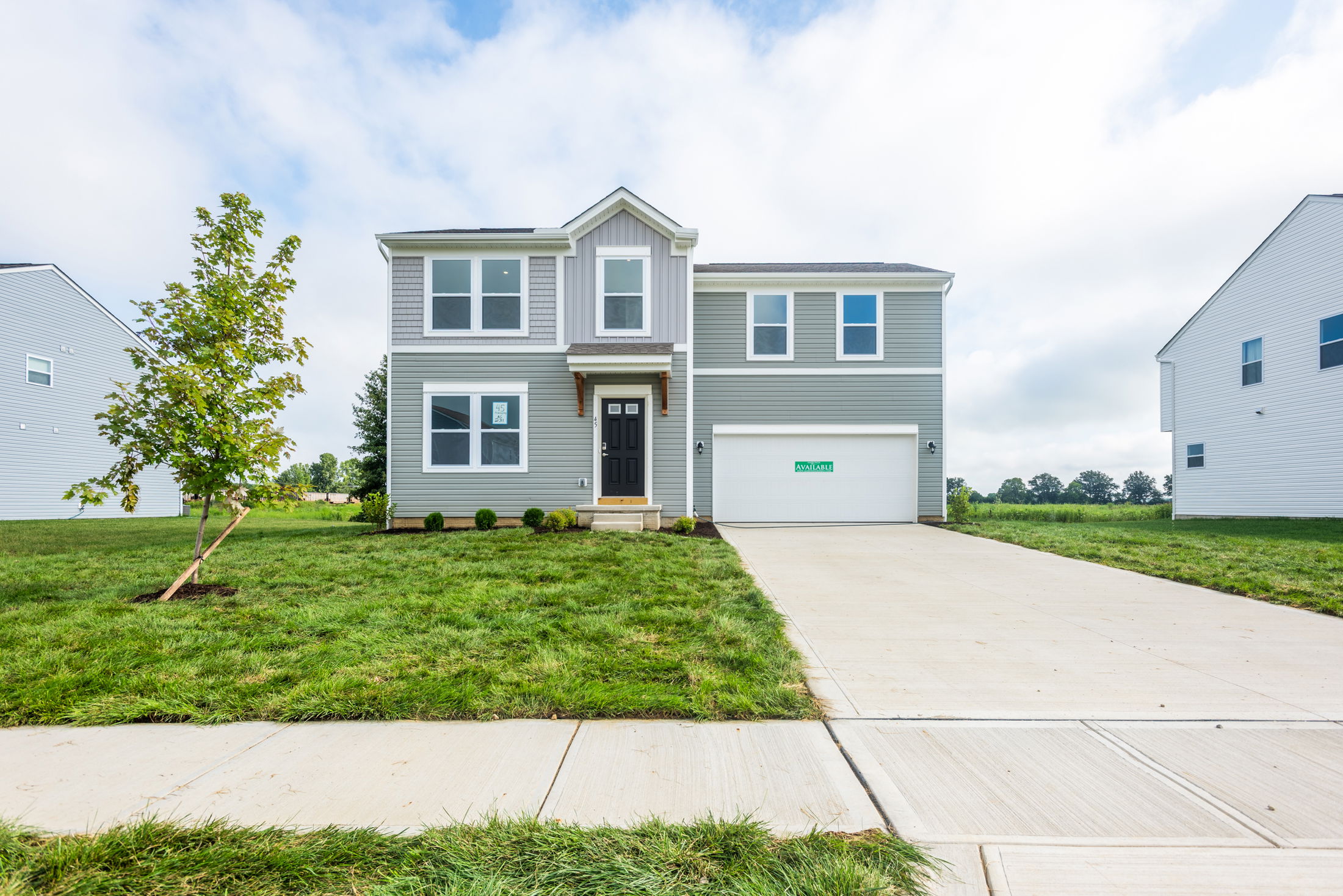 Modern two-story gray house with a well-maintained lawn and driveway.