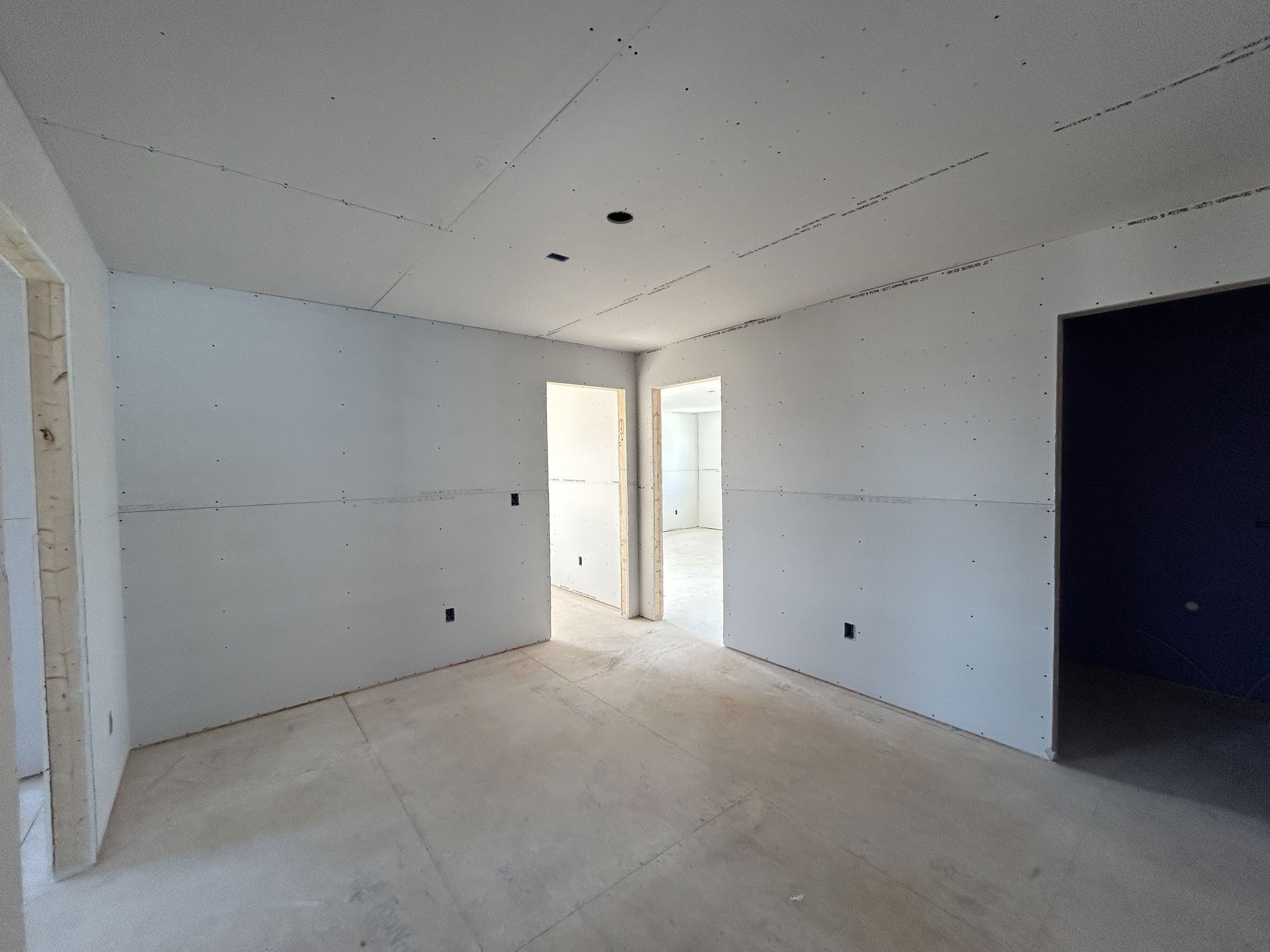 Newly constructed room featuring unfinished drywall and bare floors ready for further renovation.