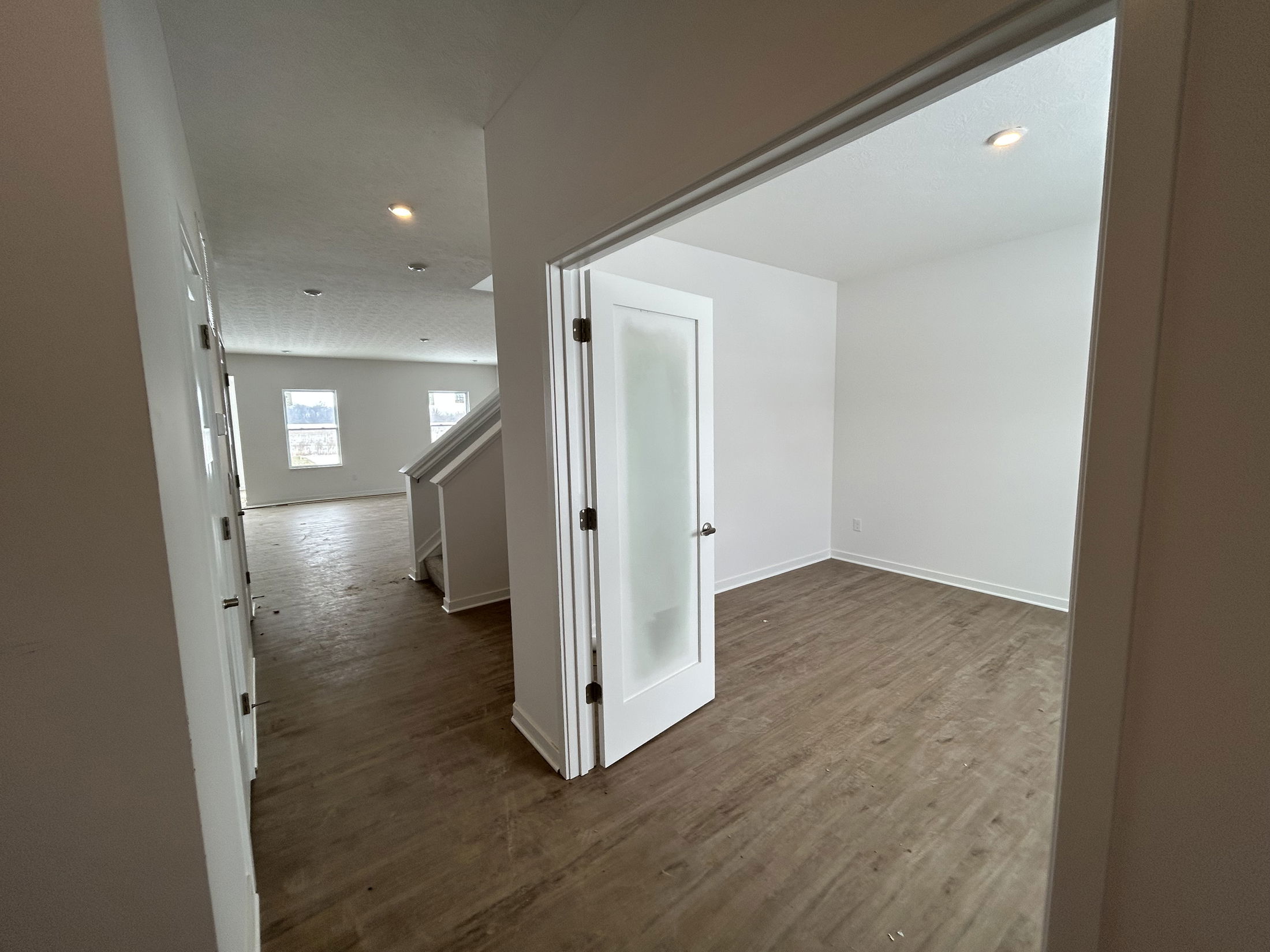 Interior view of a modern, spacious home showcasing open rooms and stylish wooden flooring.