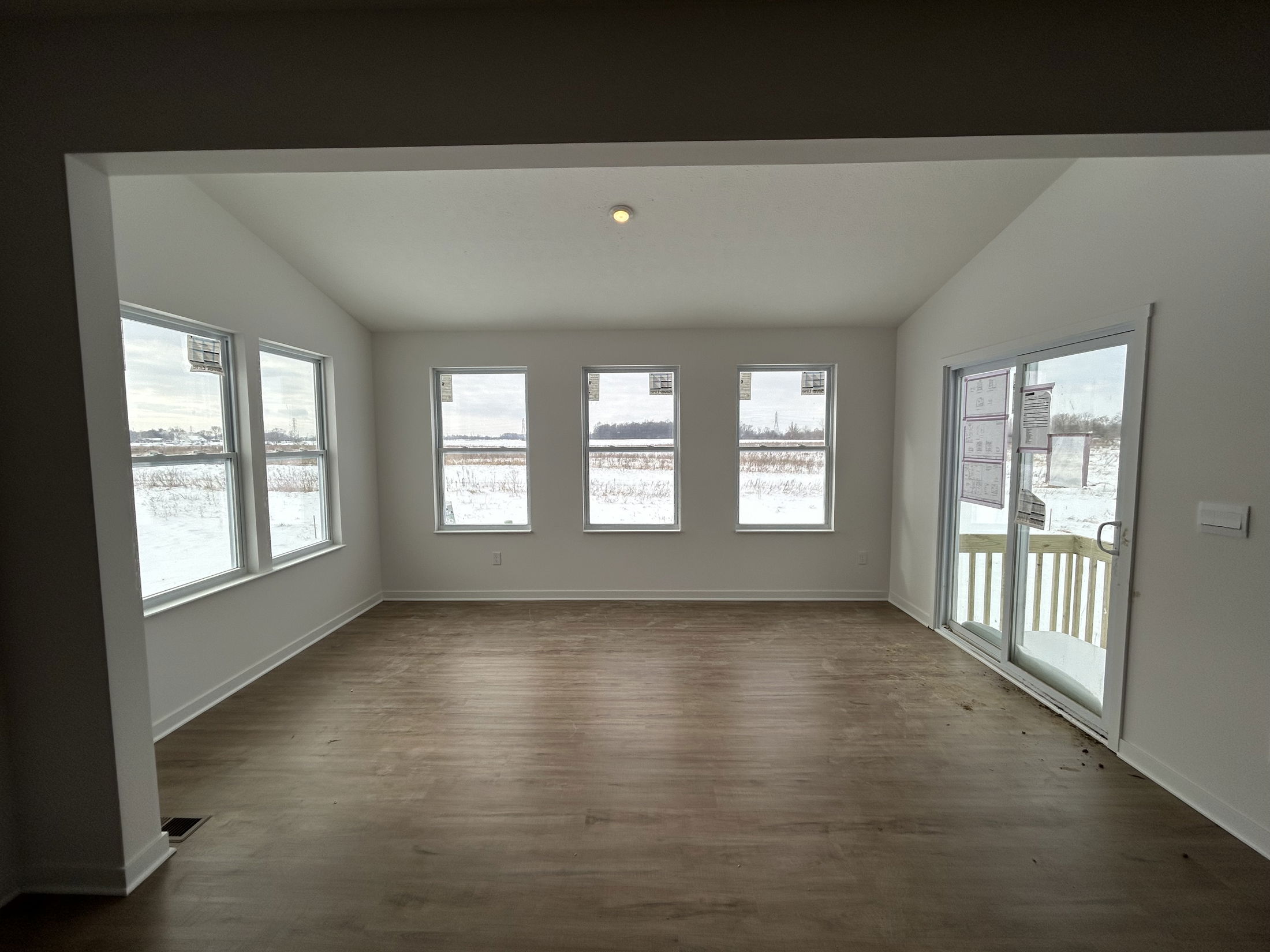 Bright and spacious sunroom with large windows overlooking a snow-covered landscape and wooden deck.
