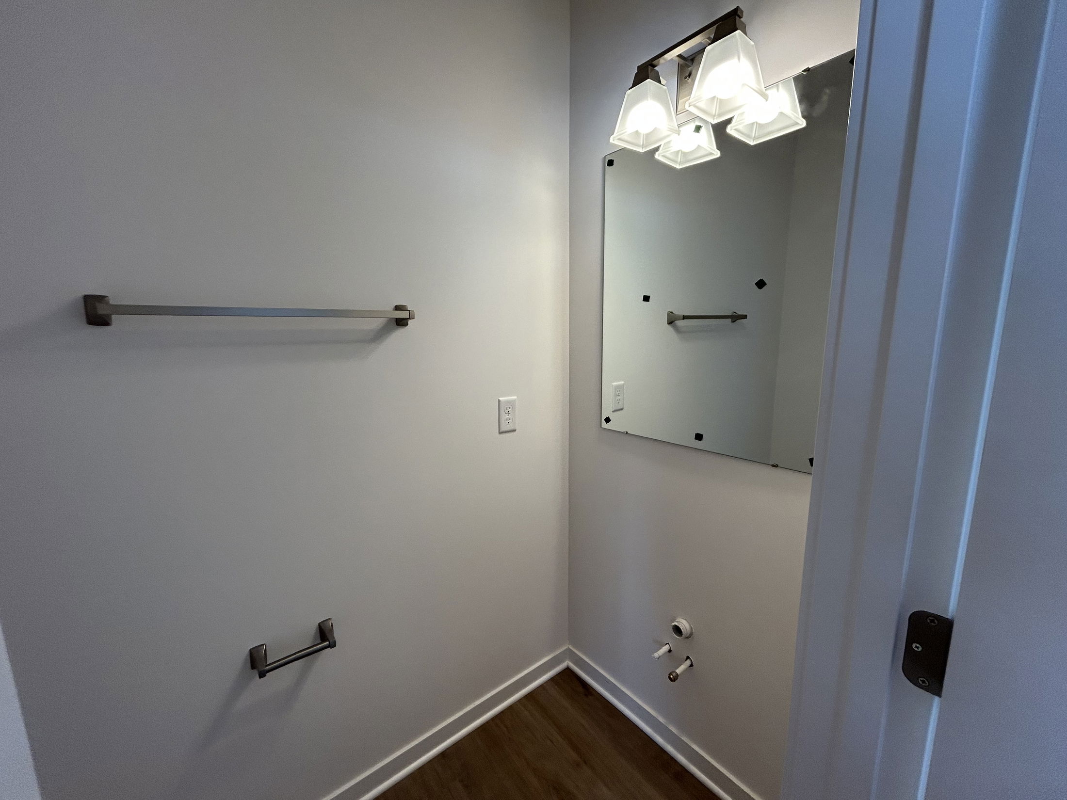 Modern bathroom interior featuring a wall-mounted mirror, stylish light fixtures, and towel bars.