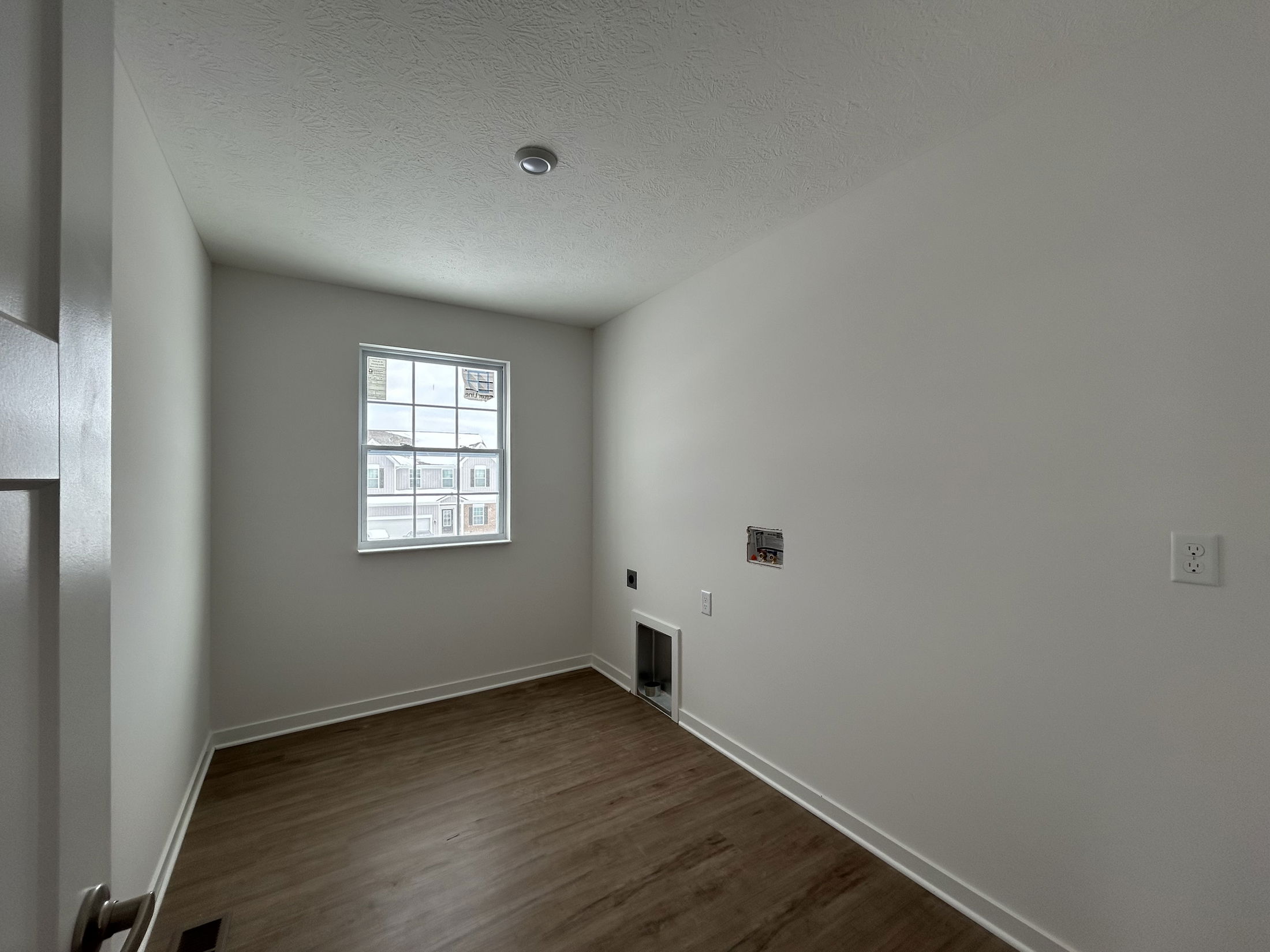 Empty room with white walls, a large window, and wooden flooring, suitable for various interior design possibilities.