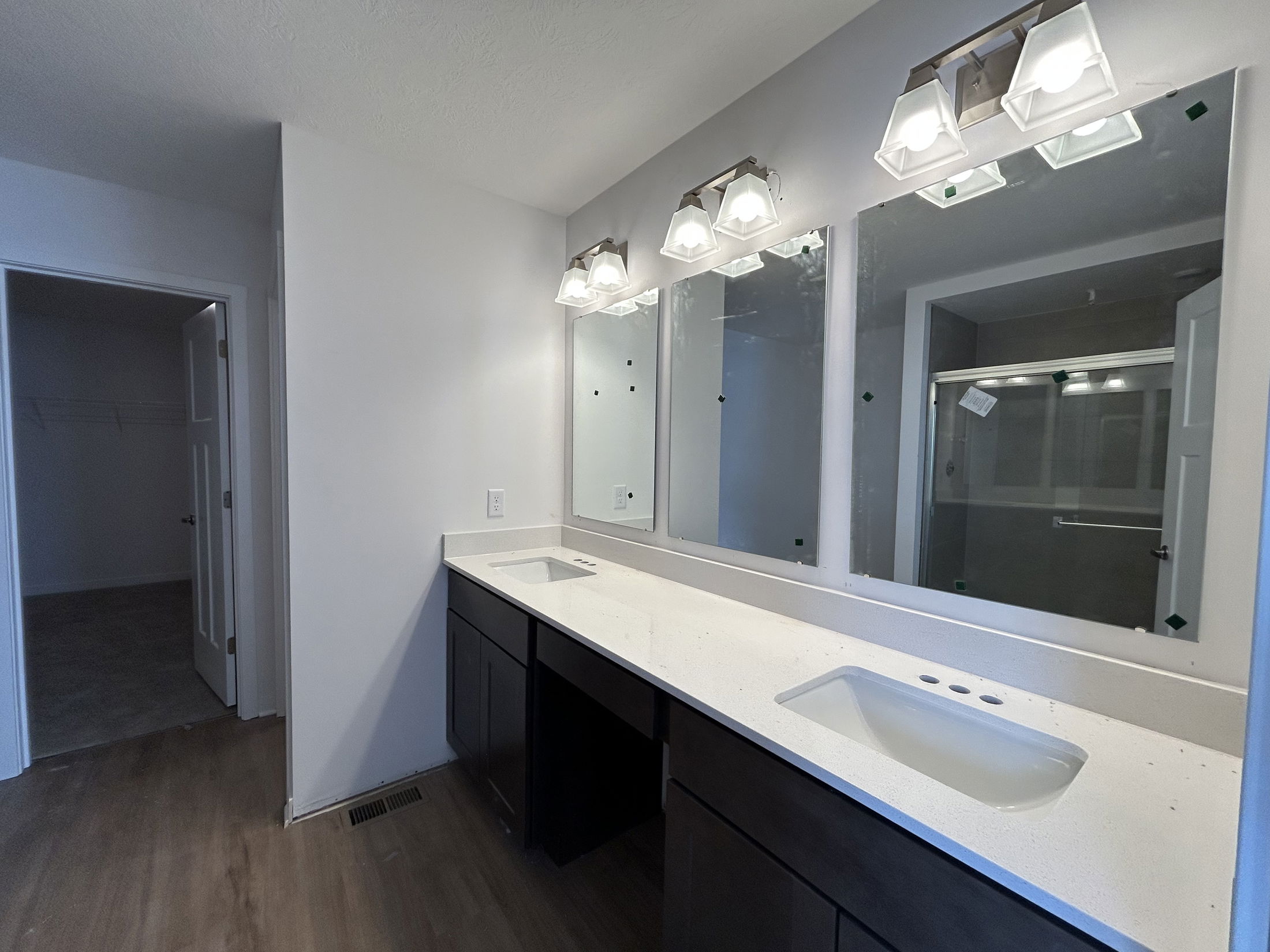 Modern bathroom interior featuring double sinks, sleek cabinets, and natural light from mirrors.