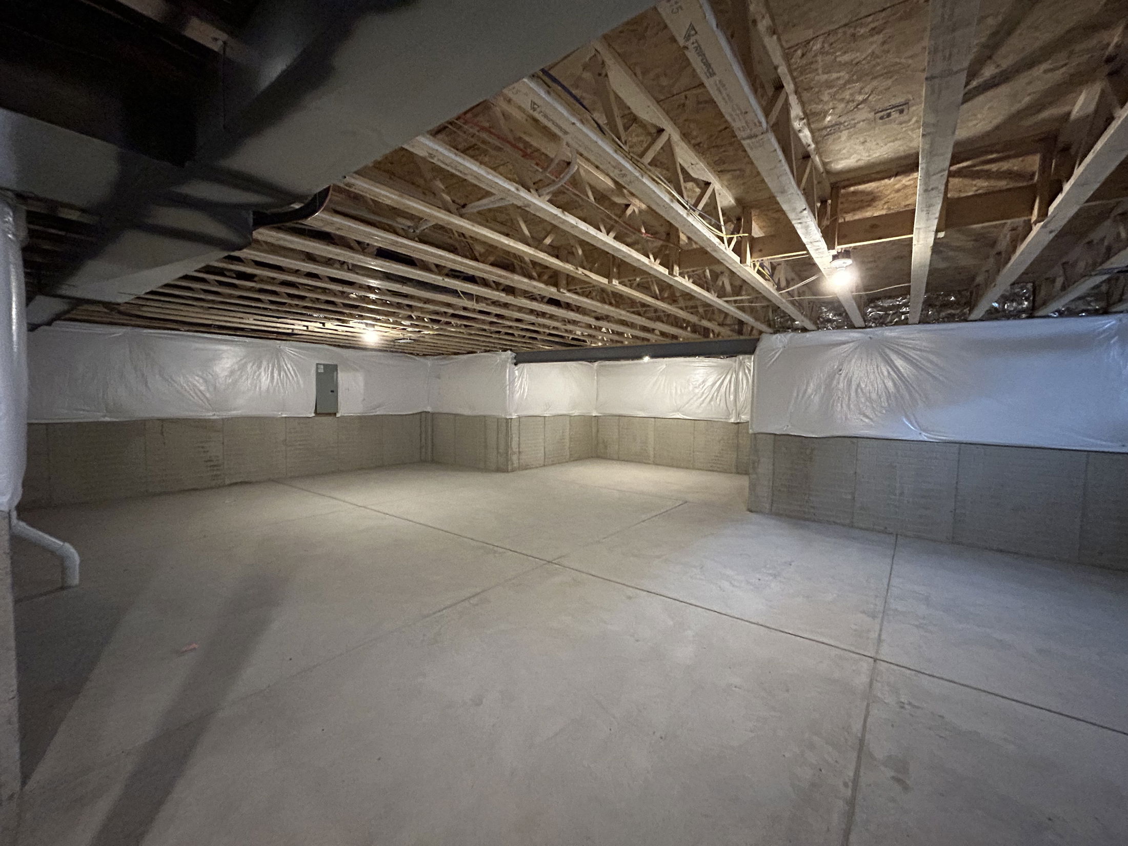Spacious unfinished basement with exposed beams and concrete flooring, providing ample space for storage or future renovations.