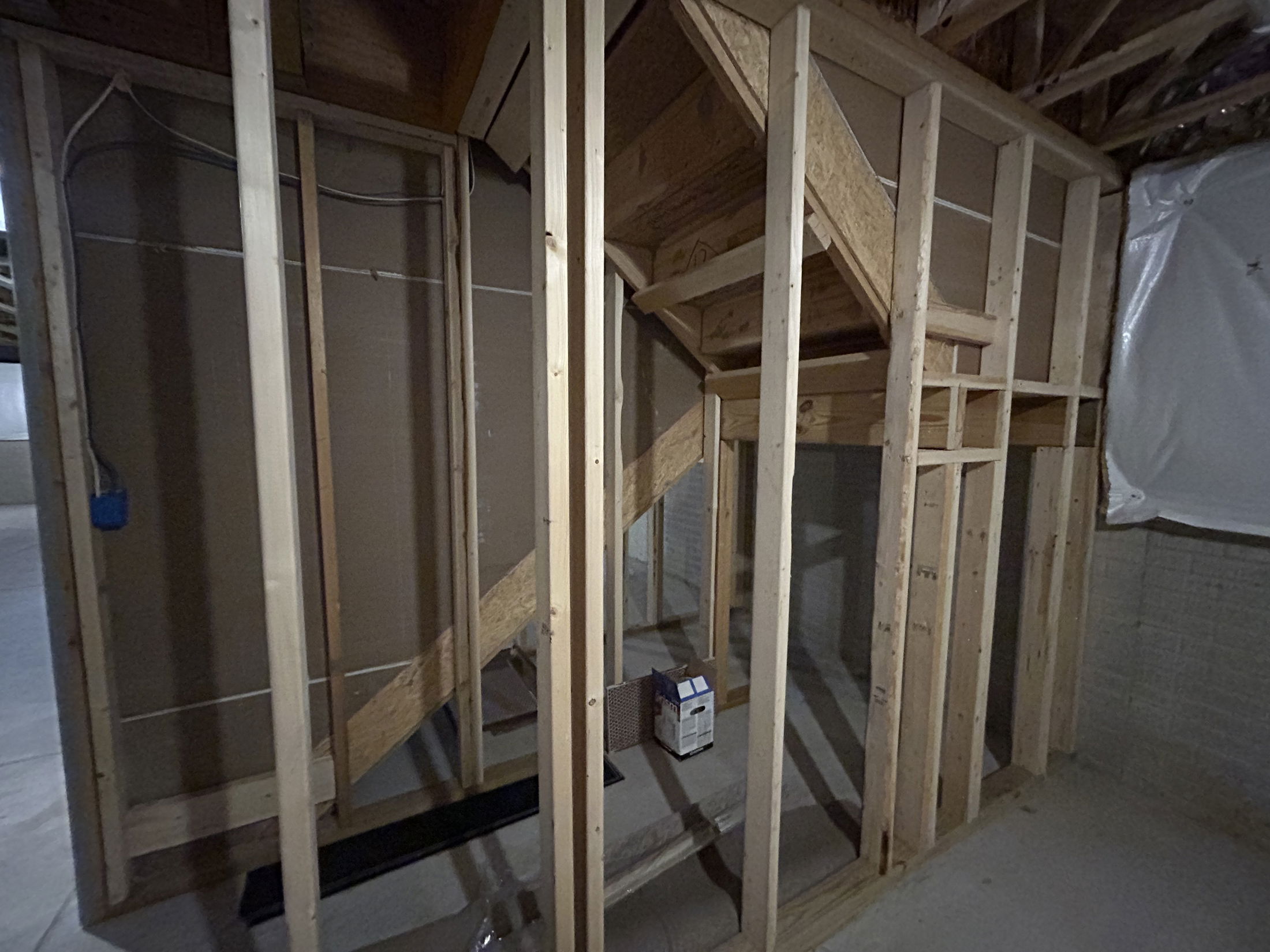 Interior view of a partially framed basement with exposed wooden structures and electrical wiring.