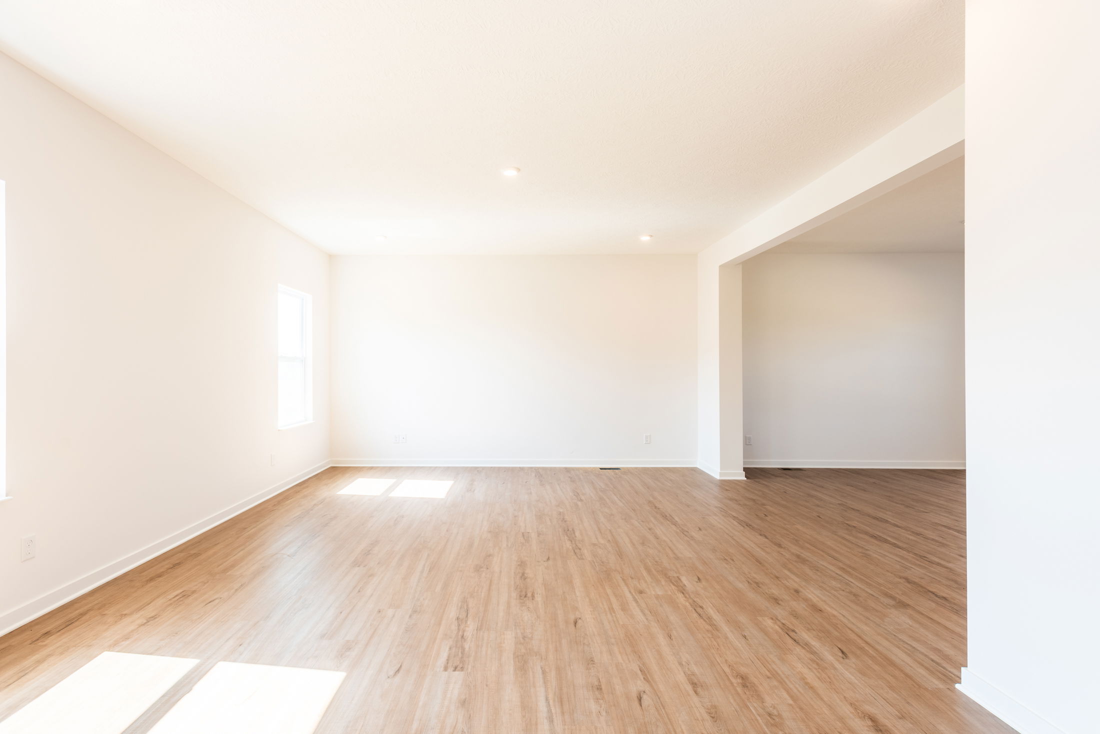 Spacious, sunlit empty room with light hardwood floors and white walls, ideal for modern home interior design.