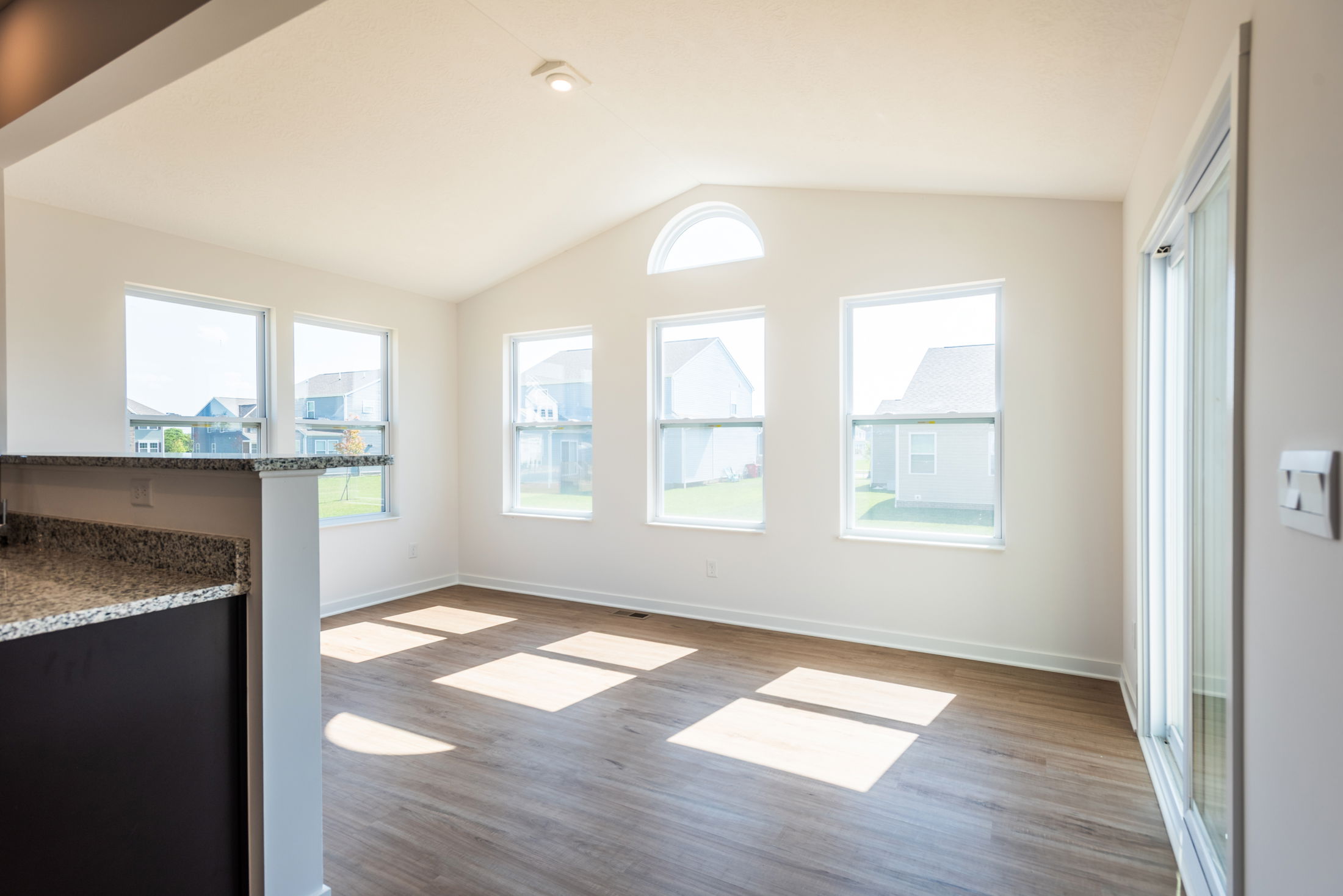 Bright, modern empty room with large windows and hardwood flooring, showcasing natural light.