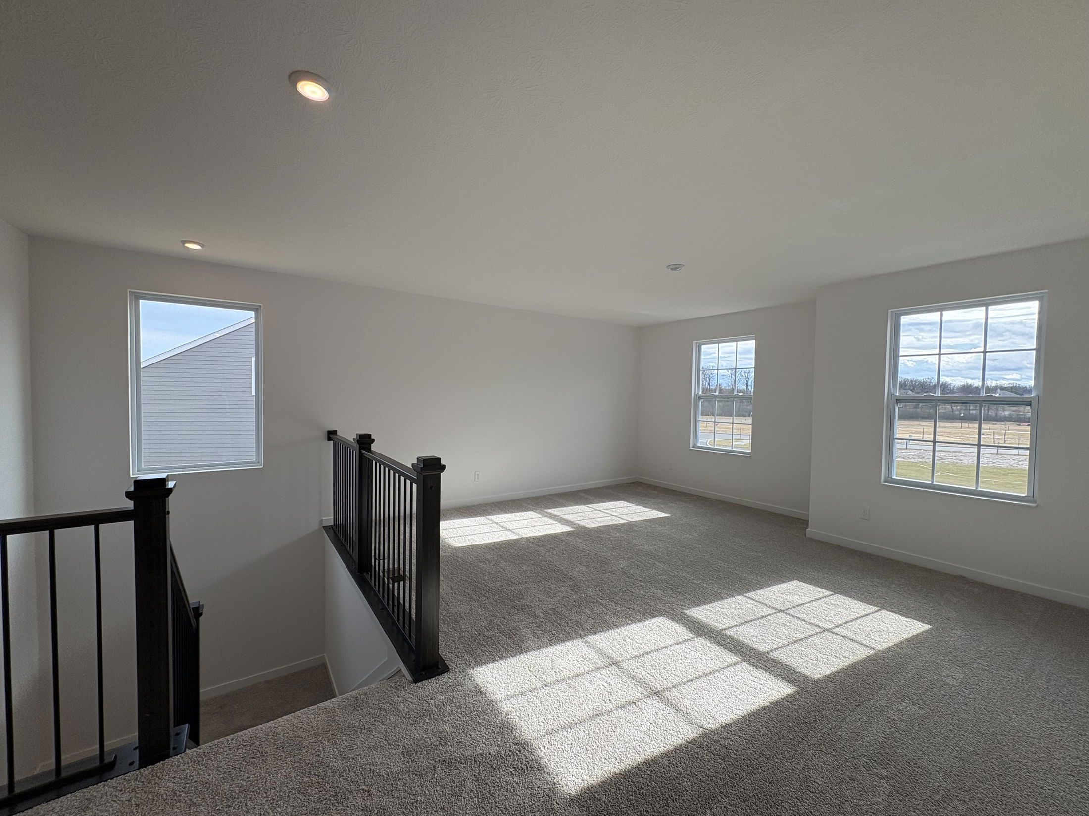 Spacious and bright upstairs living area with large windows and plush carpeting.