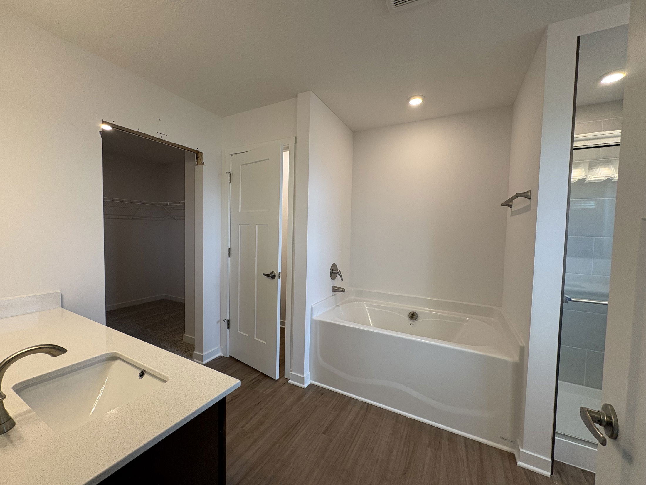 Spacious modern bathroom featuring a soaking tub, dual vanities, and a separate shower area with sleek tile accents.