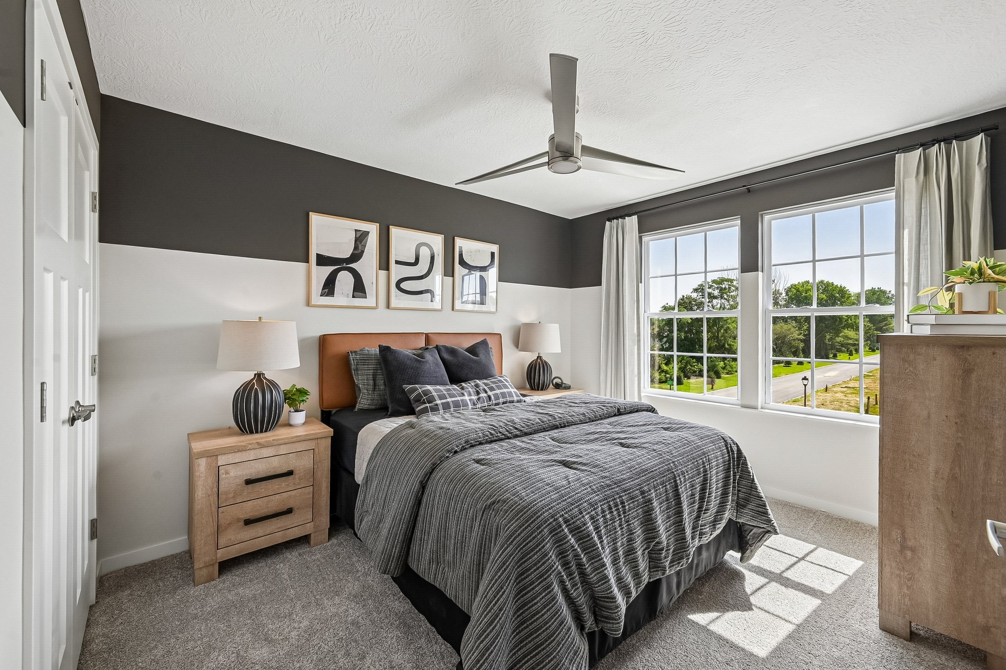 A modern bedroom featuring a gray and black color scheme, a wooden bed frame, and large windows with natural light.