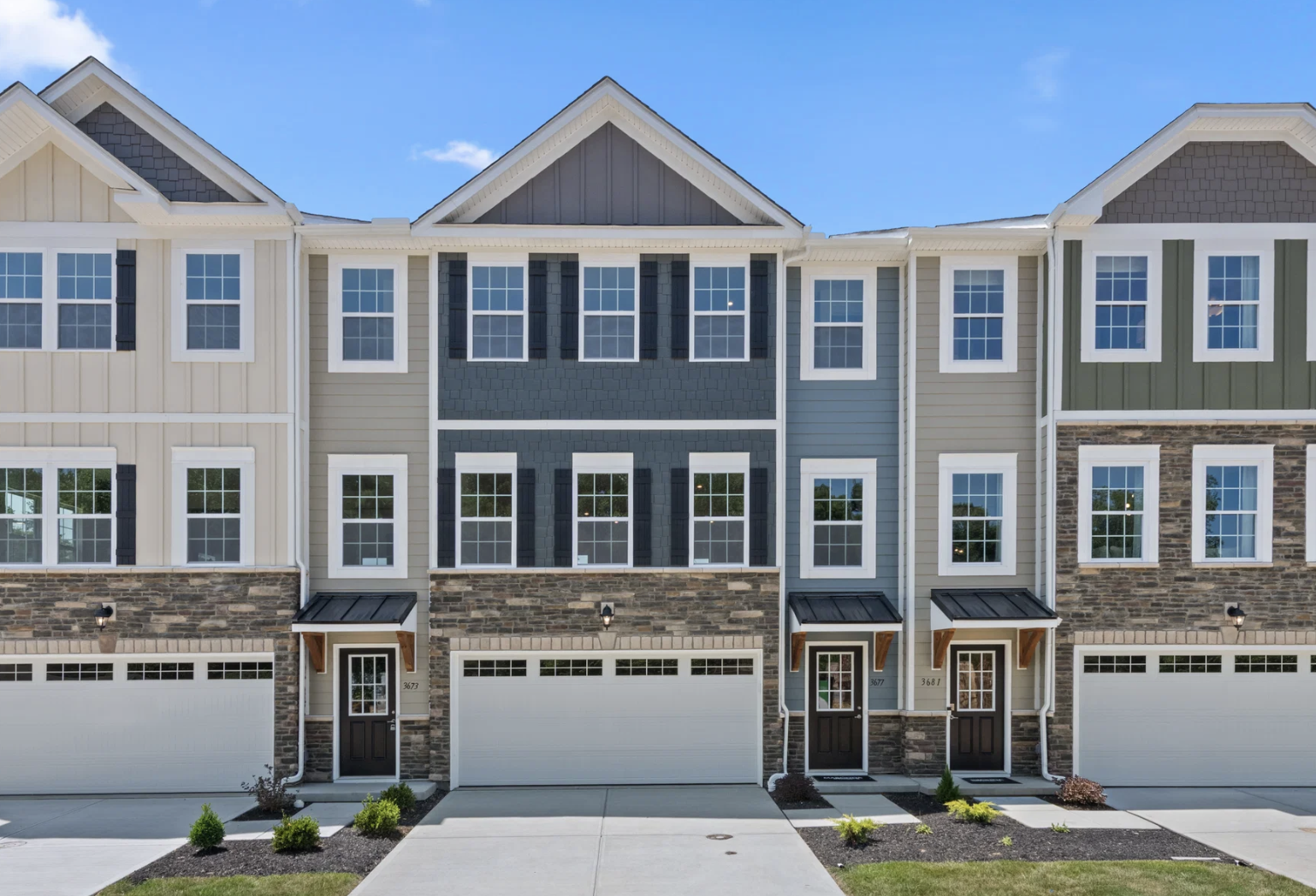Row of modern townhouses with stone and siding exteriors and garages.
