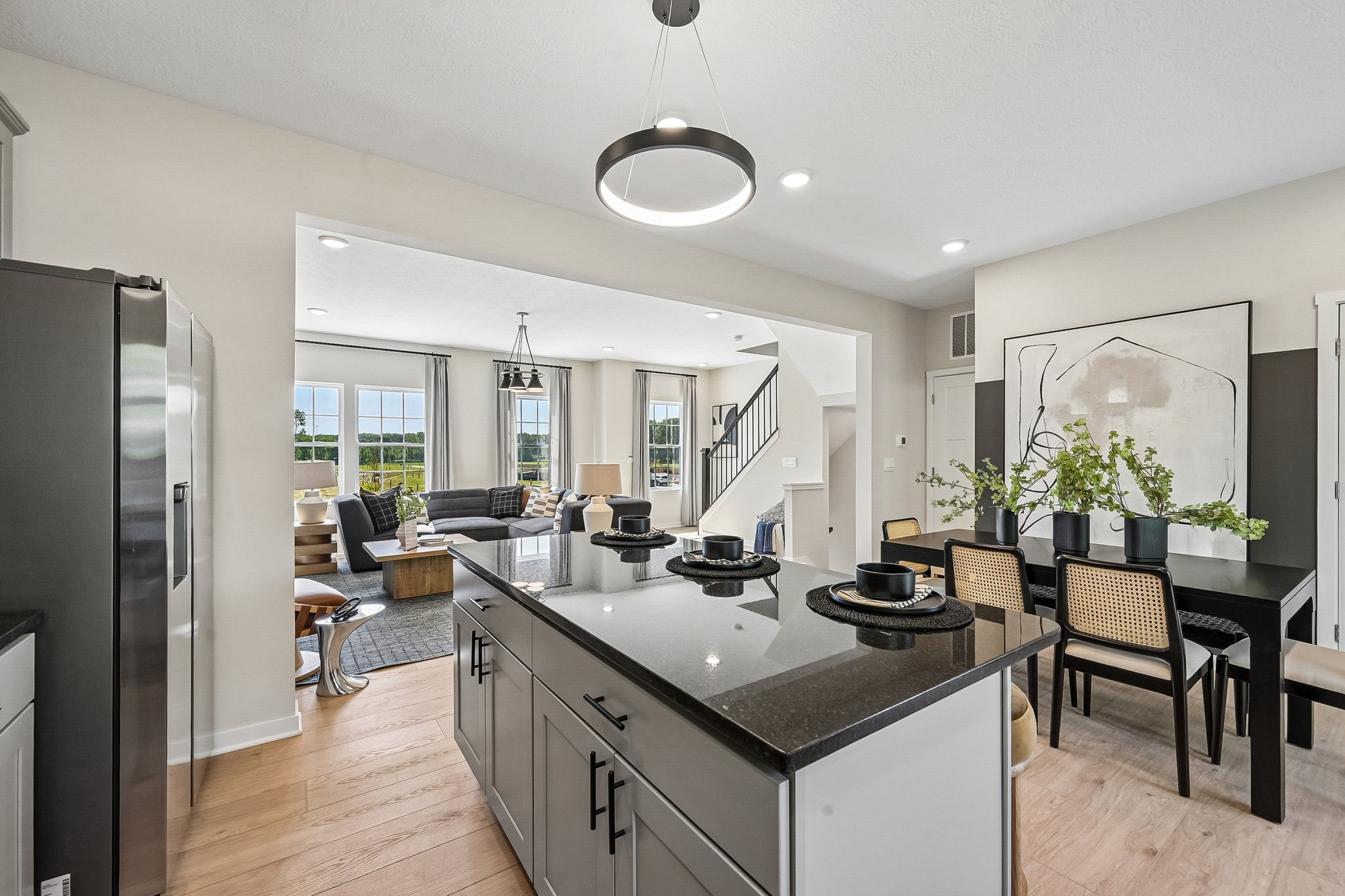 Modern kitchen with a central island, black countertops, and a view of a dining area and living room through an open layout.