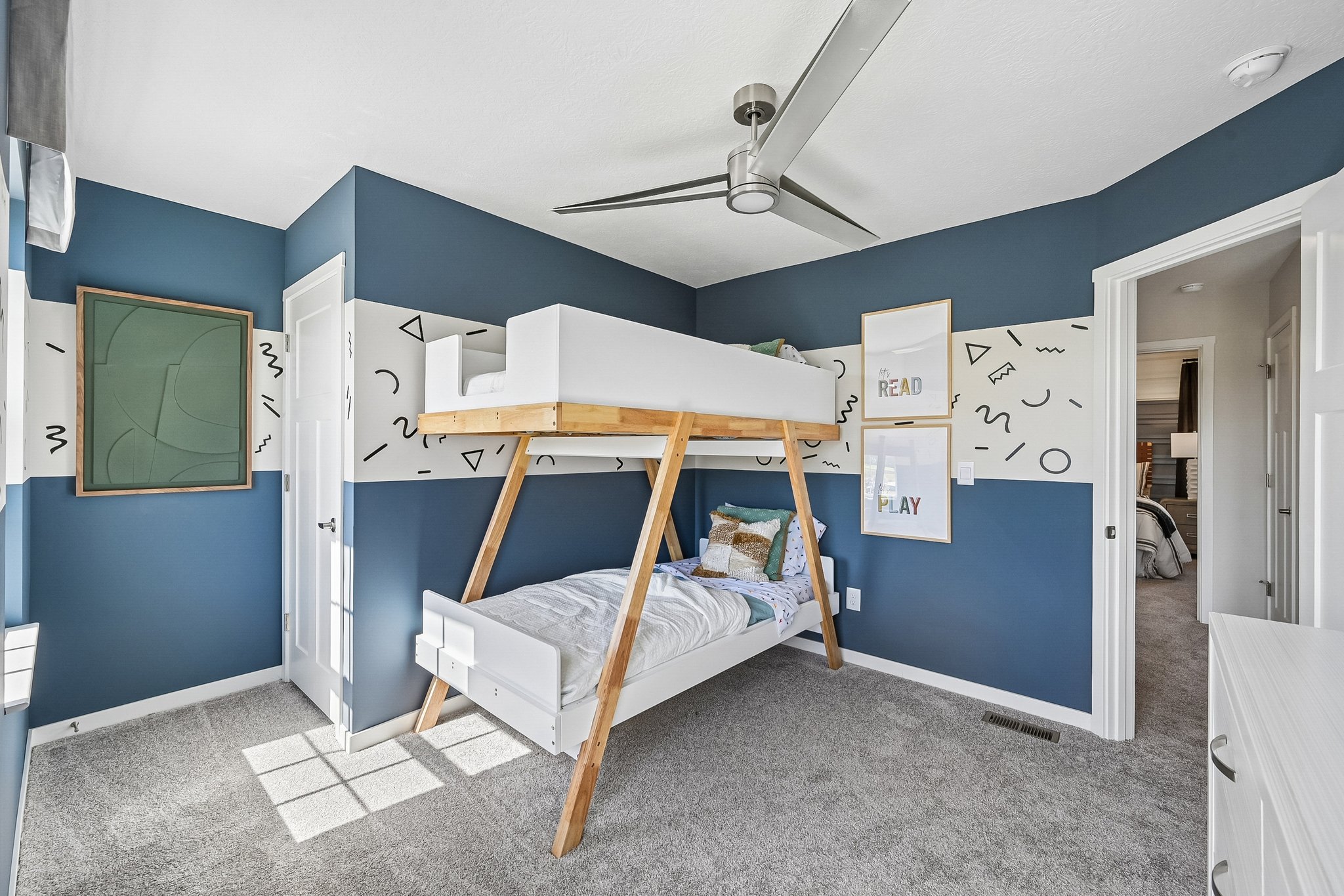 A modern children's bedroom featuring a wooden bunk bed, blue walls, and playful decor.