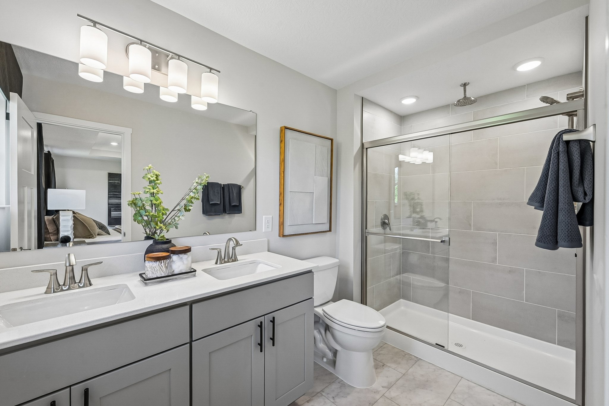 Modern bathroom featuring a double vanity with two sinks, a glass shower enclosure, and a neutral color scheme.