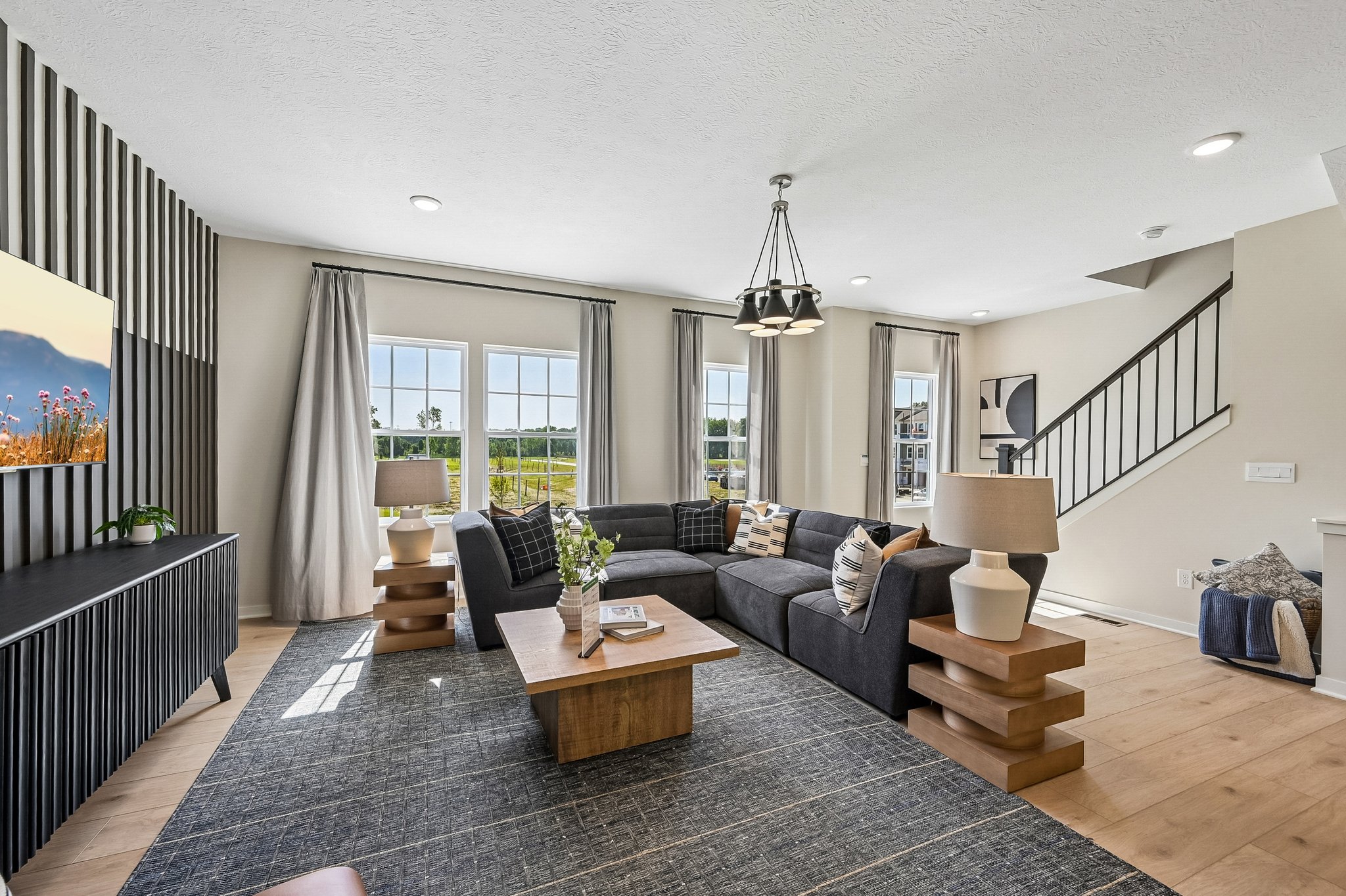 Living room featuring a sectional sofa, two lamps on side tables, a coffee table, and large windows with a scenic view.