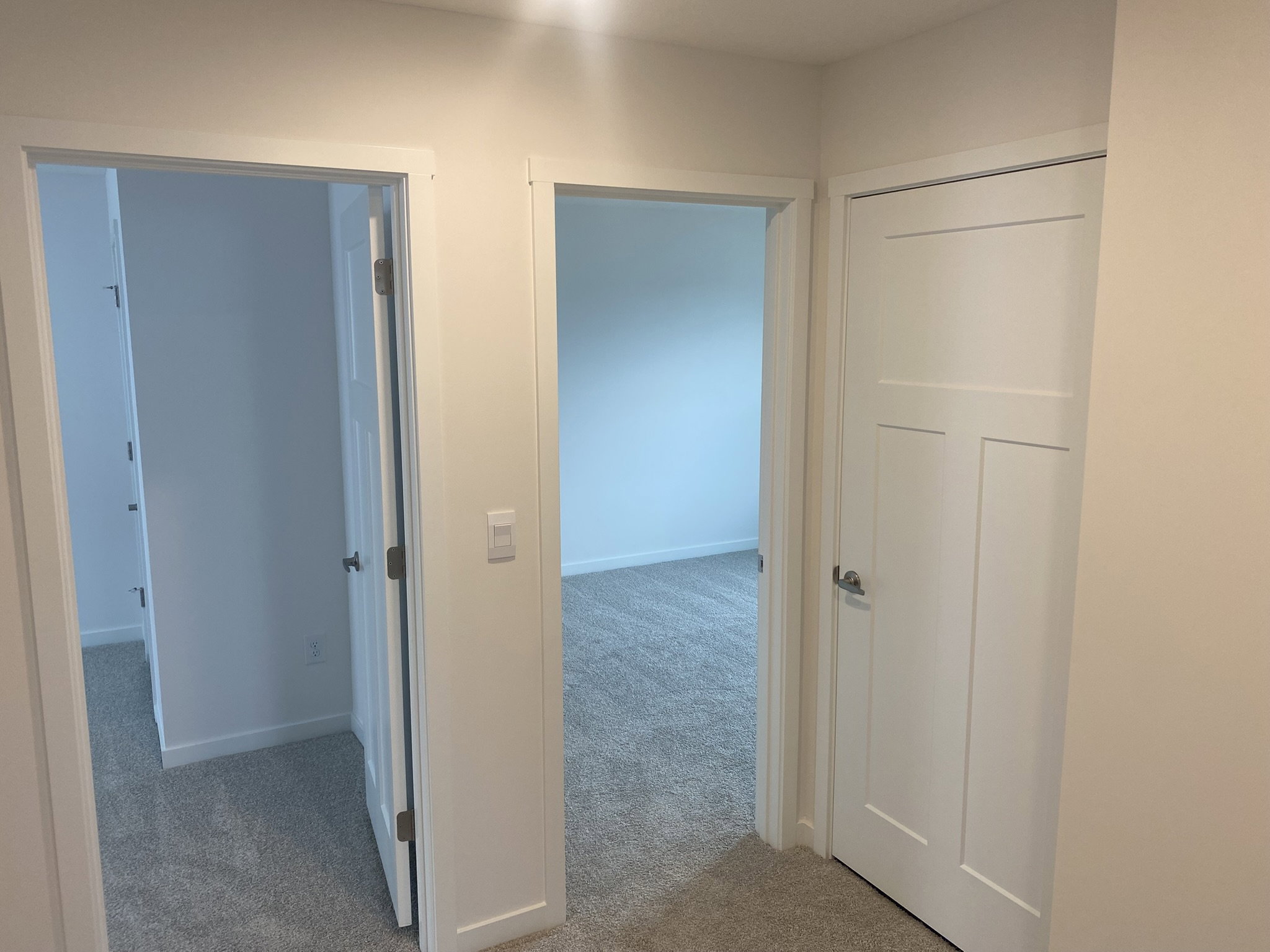 Two open doorways leading to a well-lit, carpeted room with plain white walls.