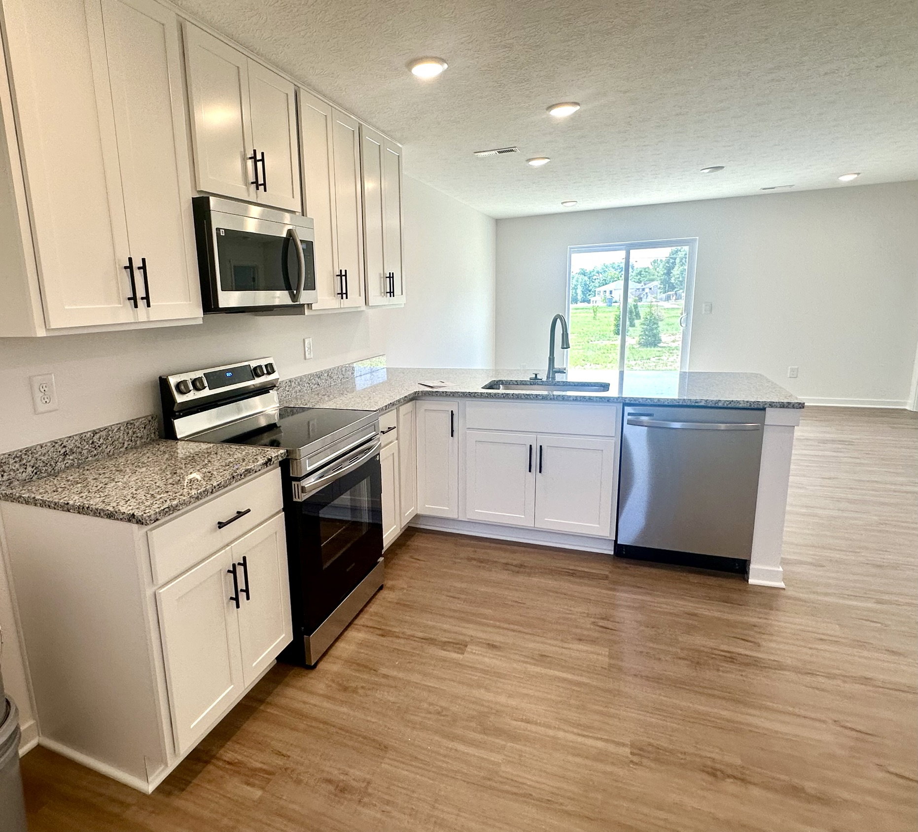 Modern kitchen interior featuring white cabinets, stainless steel appliances, and granite countertops.